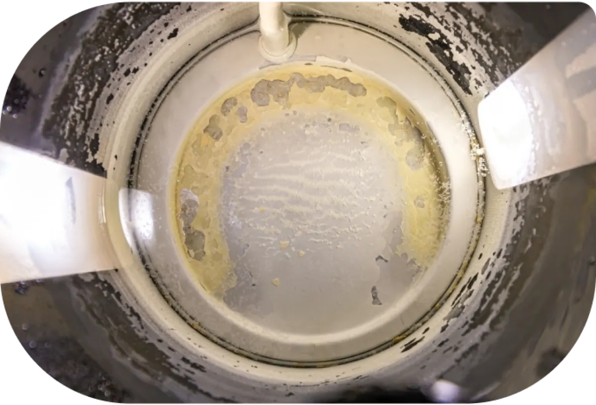 Close-up view inside a metal container with peeling white and yellow paint and light reflections.