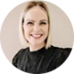 Smiling woman with short blonde hair wearing a black top, captured in a round cropped portrait.