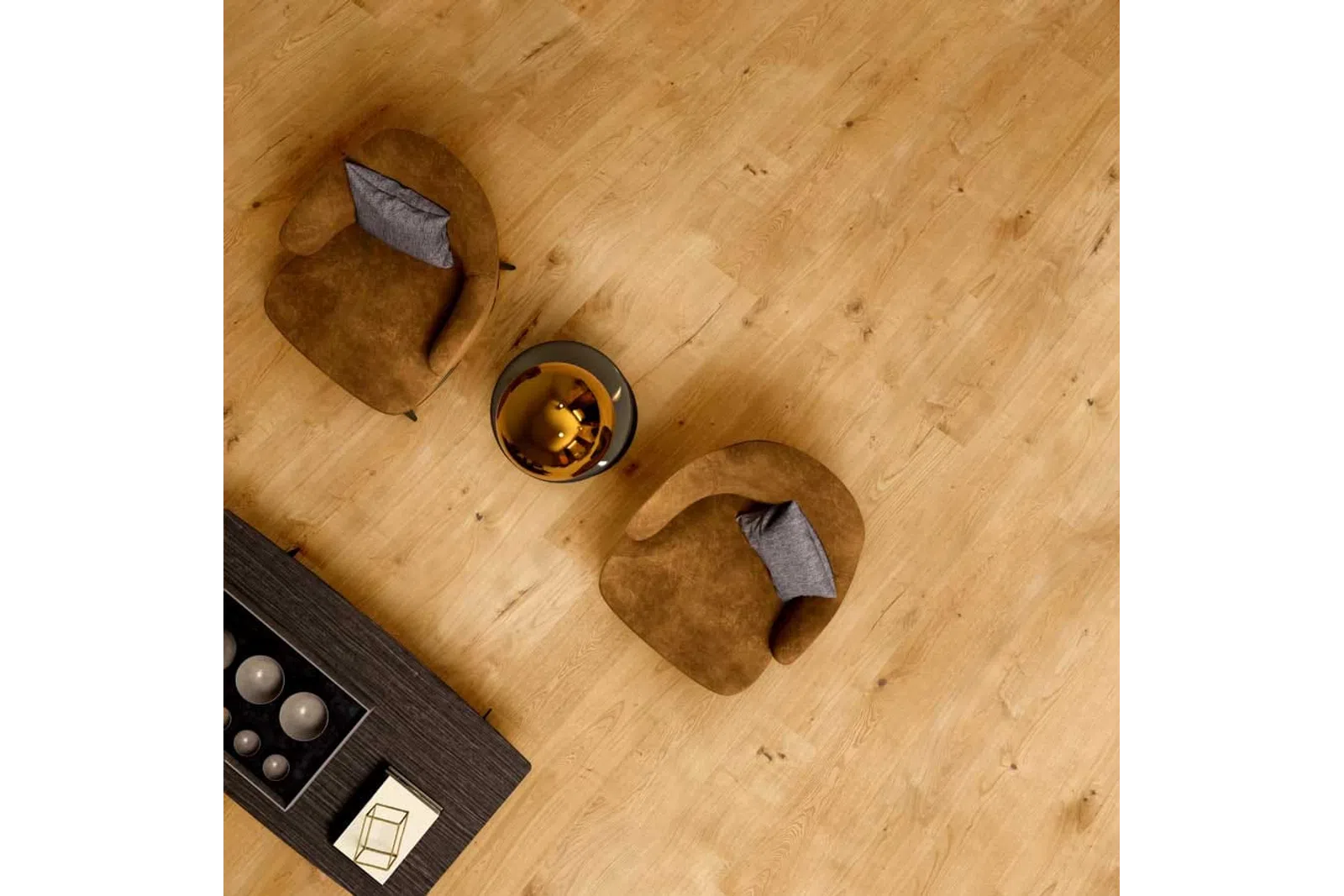 Top view of two brown armchairs with gray pillows around a round glass table on wooden floor