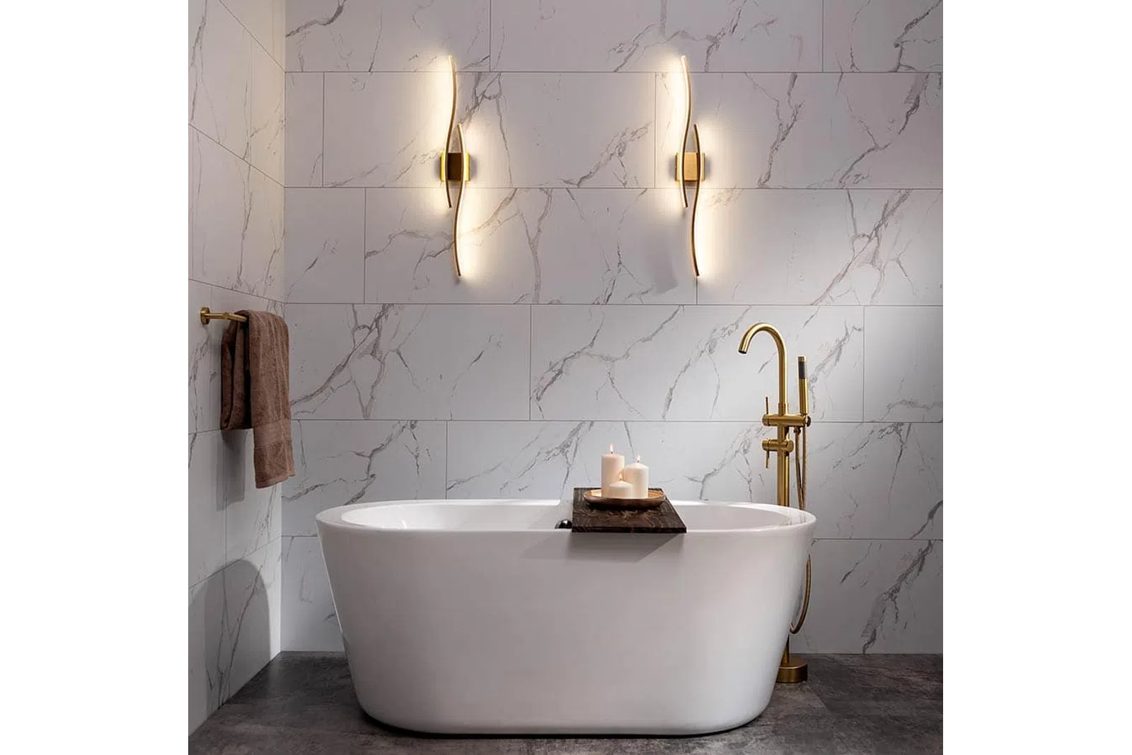 Modern bathroom with freestanding white tub, gold faucet, marble walls, candle tray, and sculptural wall lights.