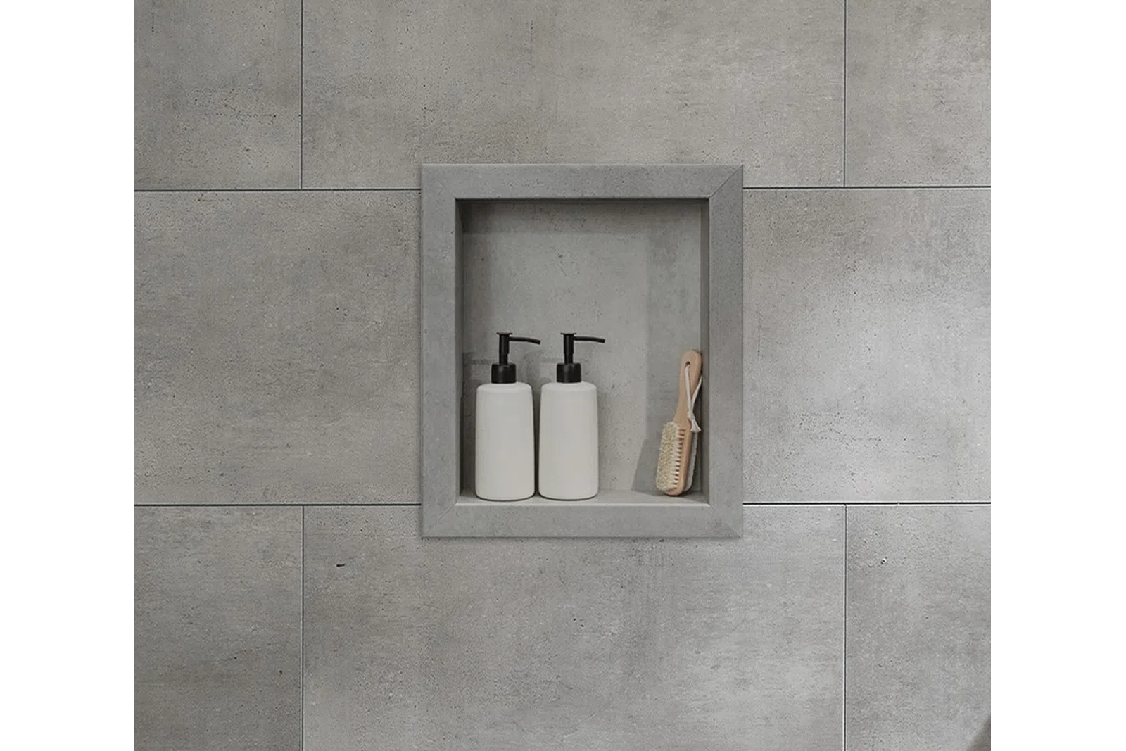 Built-in gray tiled shower niche holding two white pump bottles and a small wooden brush.