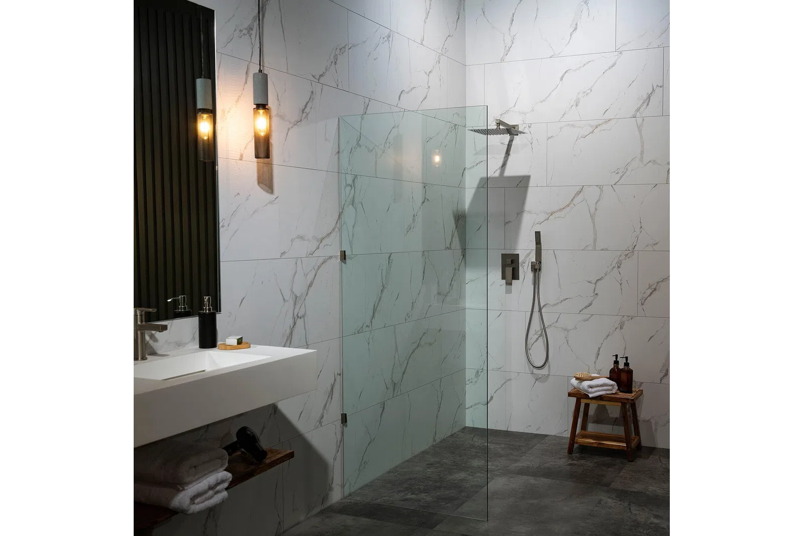 Modern bathroom with marble tiles, glass shower partition, wooden stool, and pendant lighting