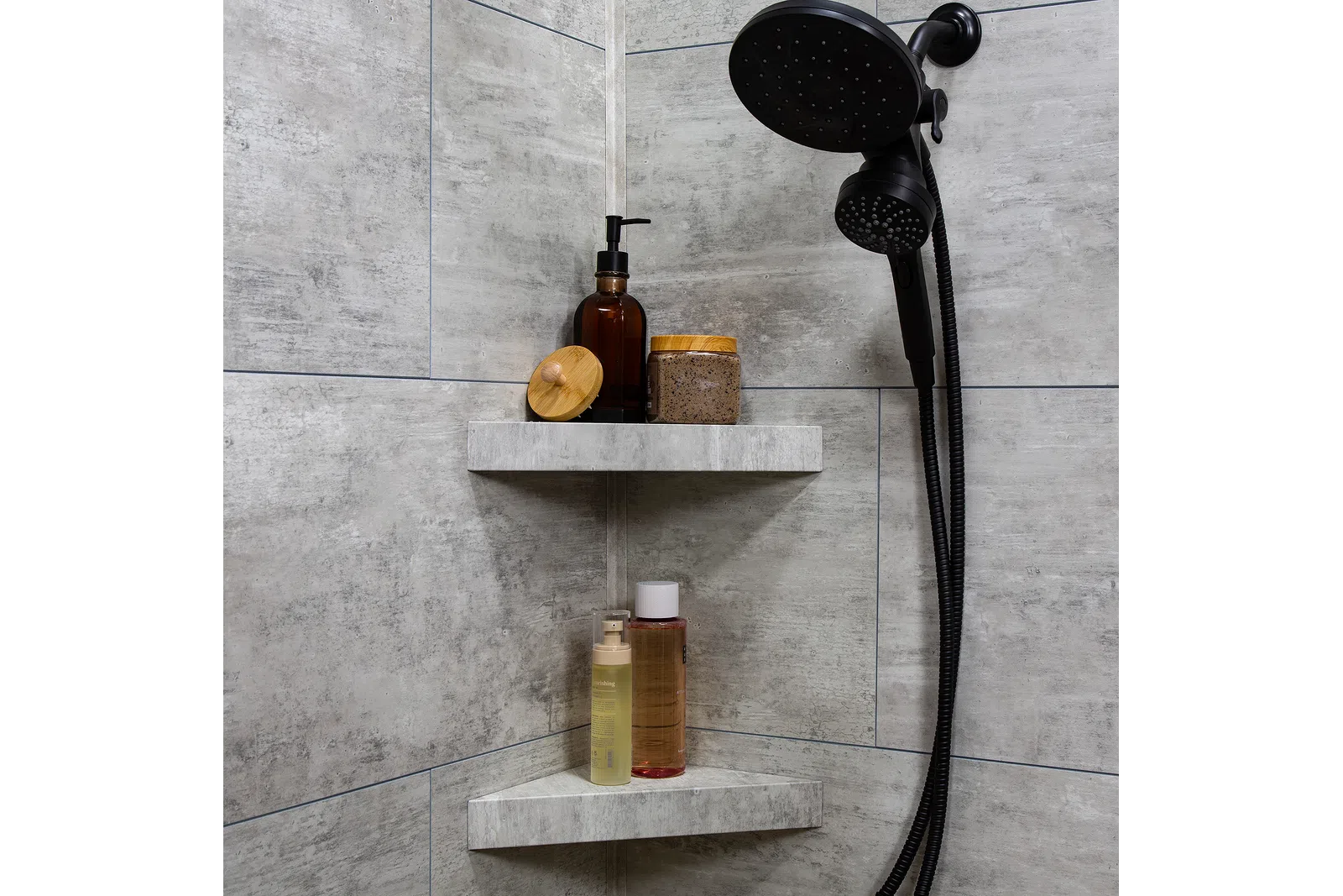 Modern shower corner with black showerhead and shelves holding toiletries in a gray tiled bathroom.
