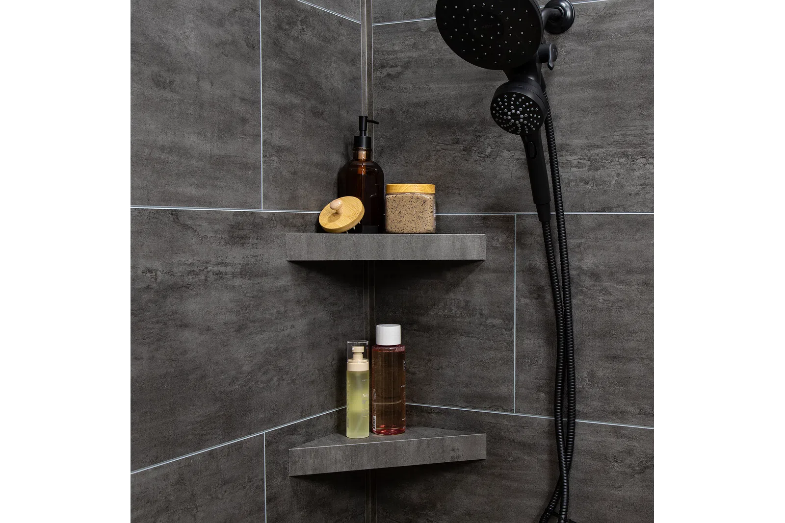 Modern corner shower shelves with bottles and jars against dark gray tiled bathroom walls.