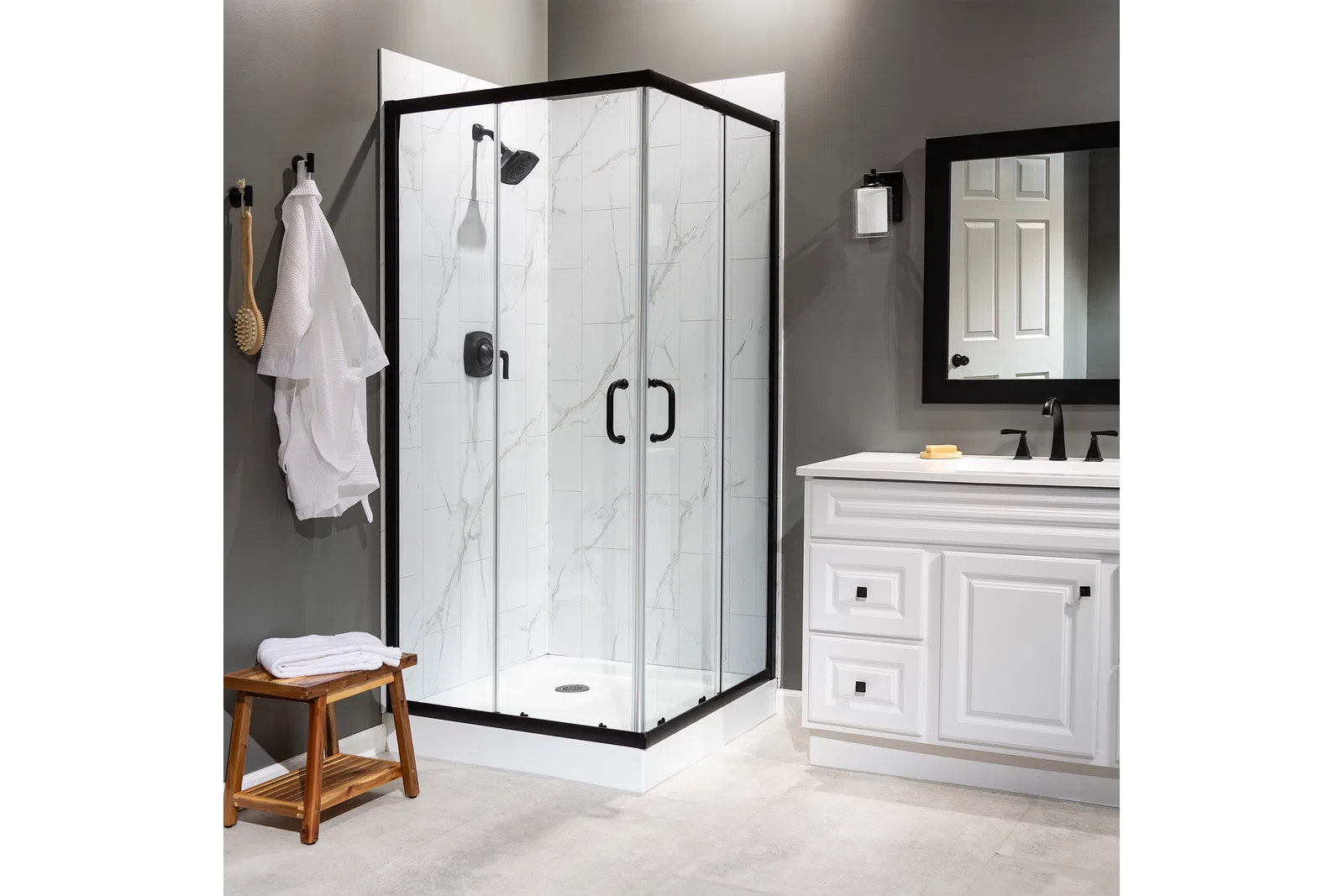 Modern bathroom with glass shower enclosure, white marble tiles, black fixtures, and white vanity with mirror.