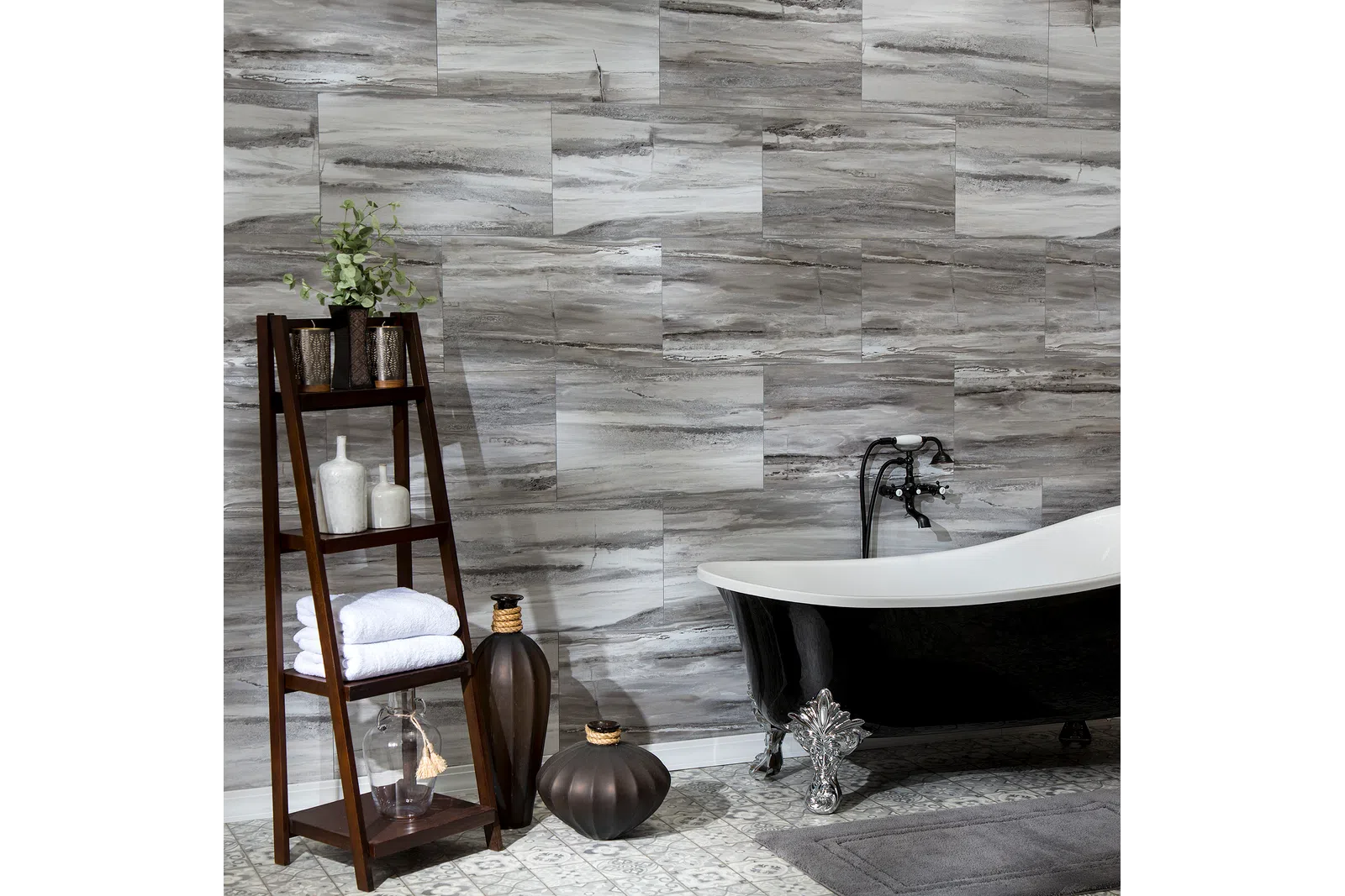 Modern bathroom with a black clawfoot tub, wood shelf holding towels and decor, and gray marble wall tiles.