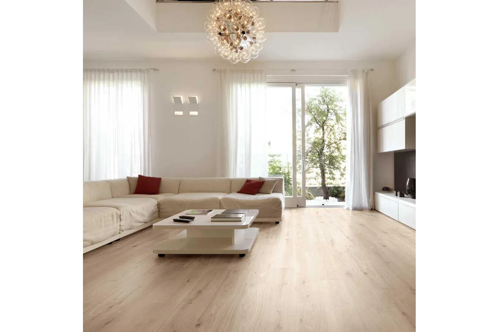 Modern living room with beige sectional sofa, wooden floor, white coffee table, large windows, and chandelier lighting