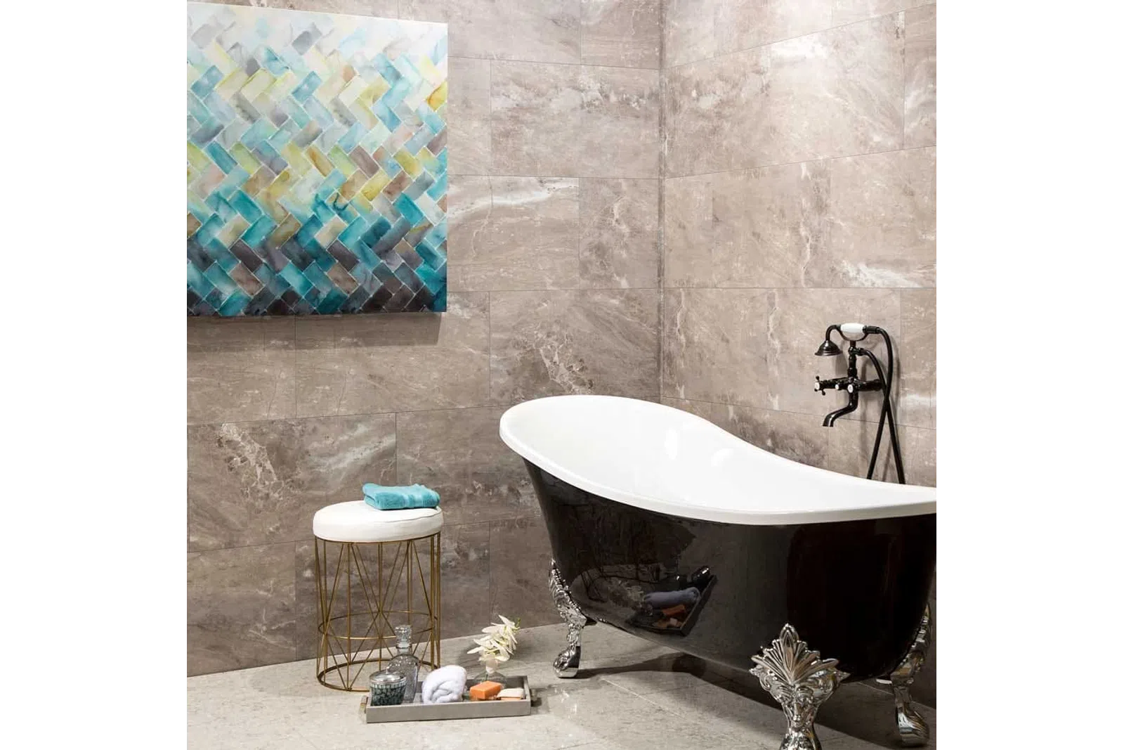 Elegant black clawfoot bathtub with vintage faucet in modern beige tiled bathroom with abstract wall art and stool.
