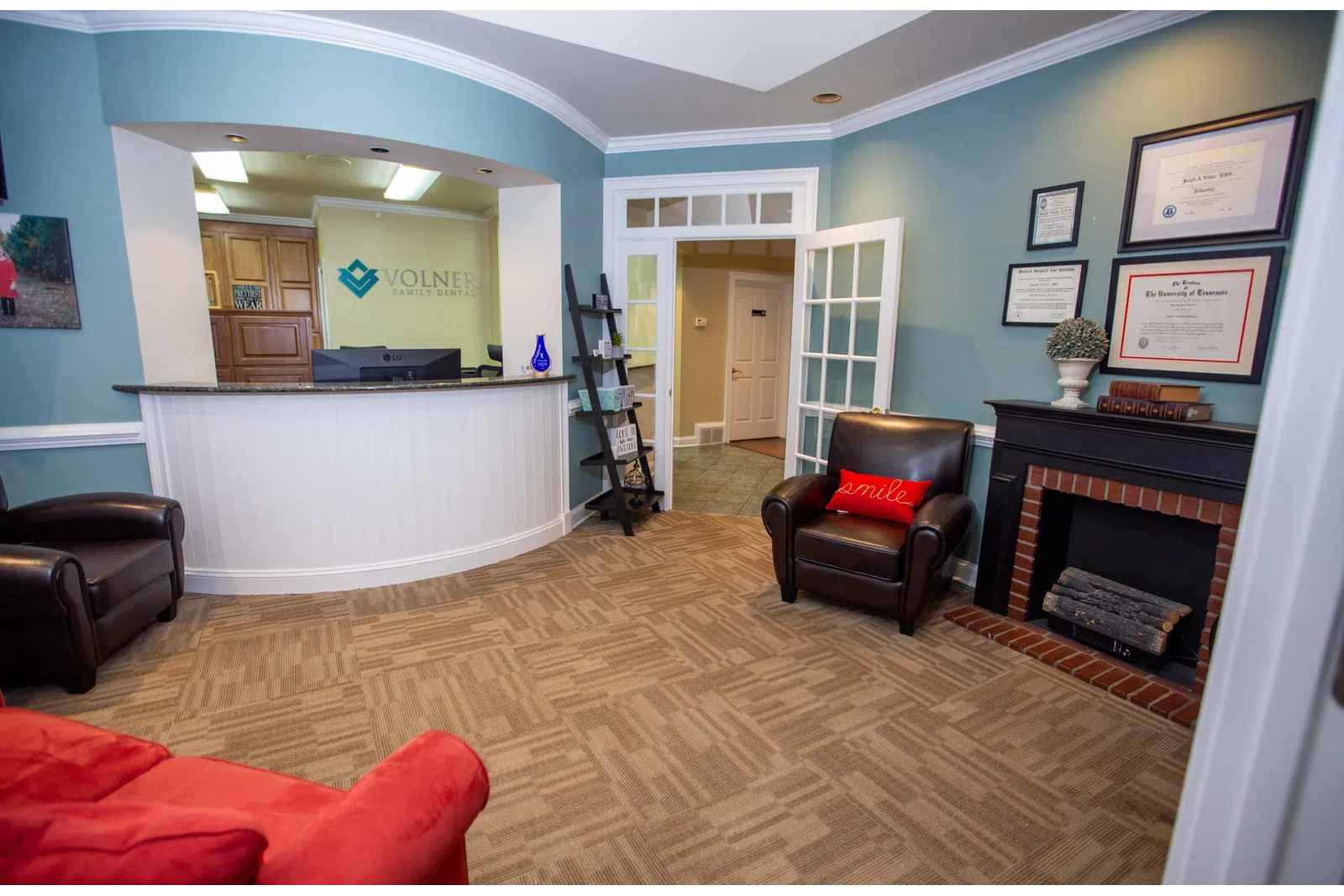 Reception area of Volner Family Dentistry with seating, front desk, certificates, and calming blue walls.