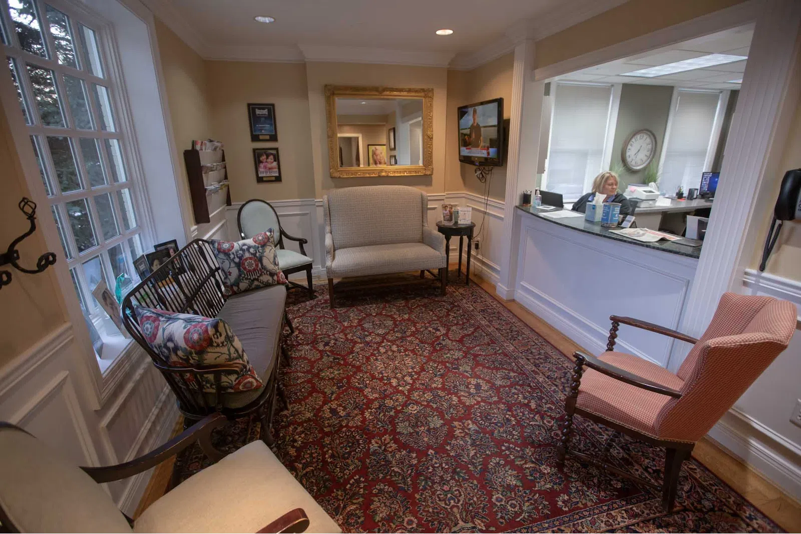 Cozy waiting room with cushioned chairs, patterned rug, a reception desk, and warm lighting in a professional setting