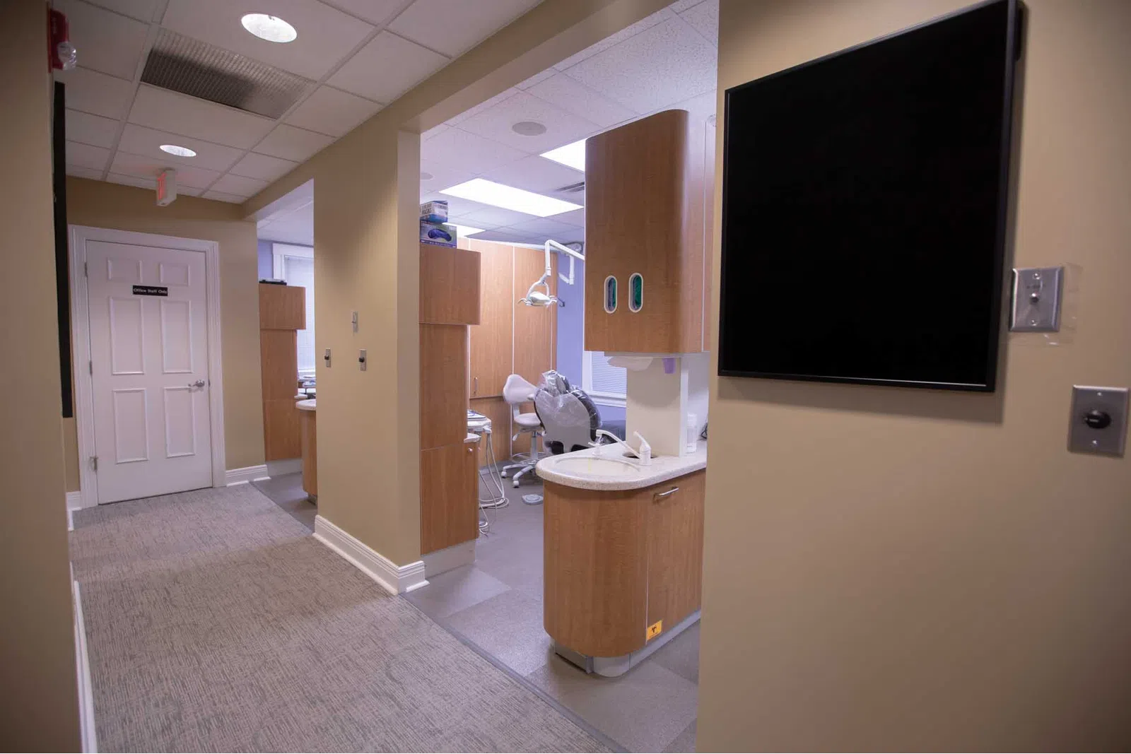 Modern dental clinic interior with beige walls, dental chair, and cabinetry in a clean, organized space
