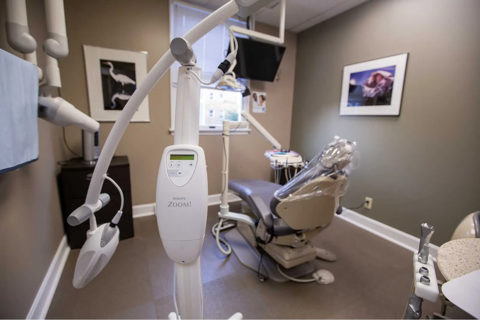 Modern dental office with Philips Zoom teeth whitening machine and dental chair covered in plastic.