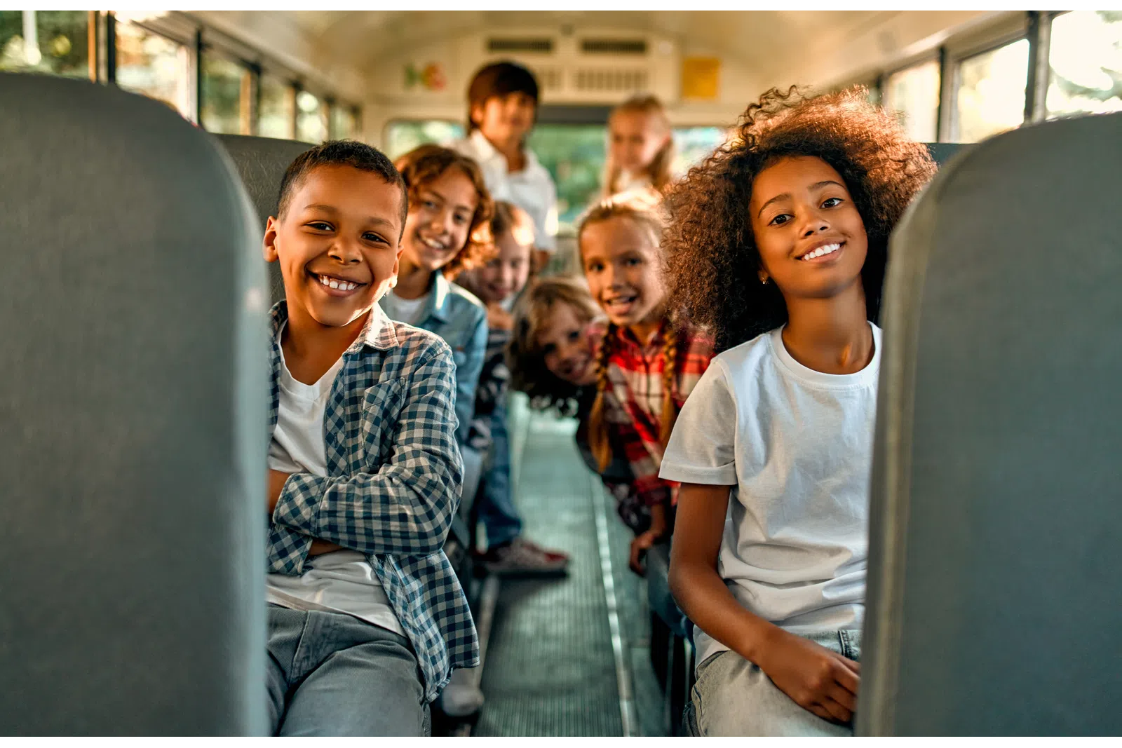 Happy diverse children smiling together on a school bus, showcasing friendship and joy.