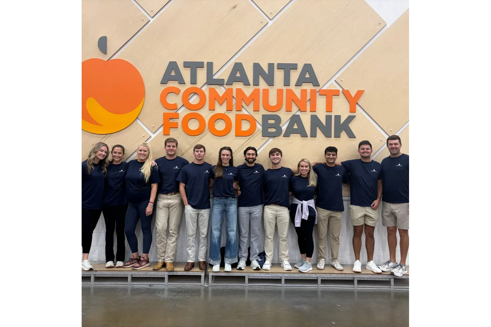 Group of volunteers standing in front of Atlanta Community Food Bank sign with overlaid text reading Atlanta Community Food Bank