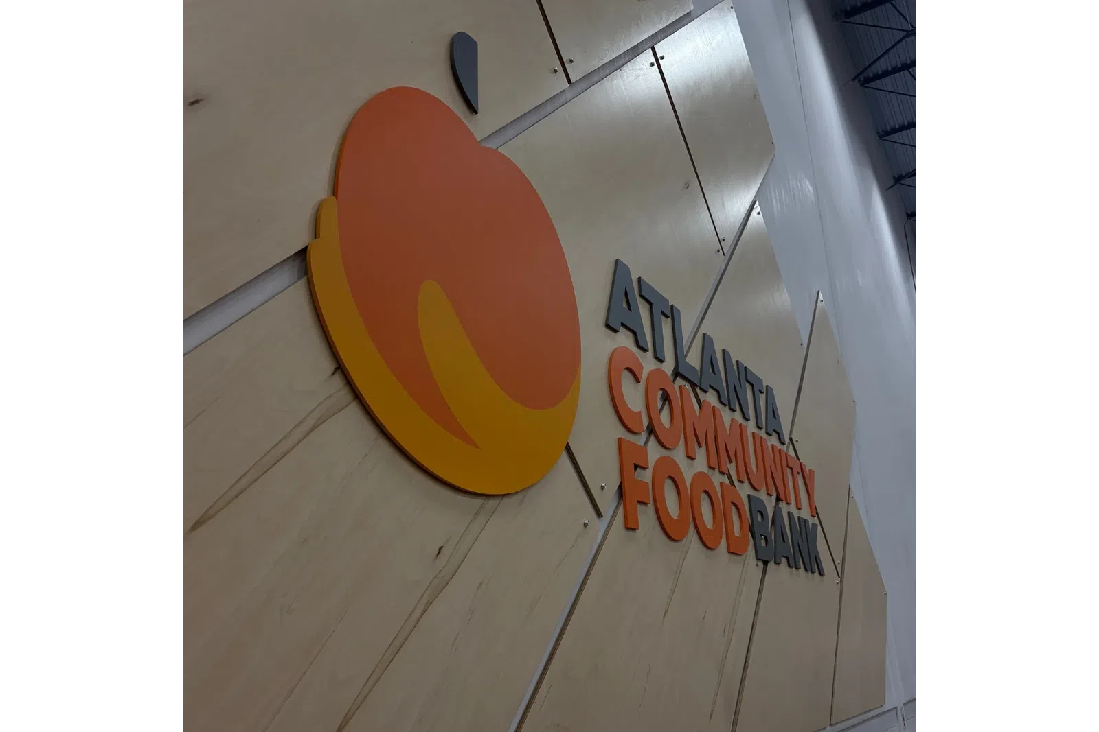 Wall sign with large orange and yellow fruit logo and text reading Atlanta Community Food Bank