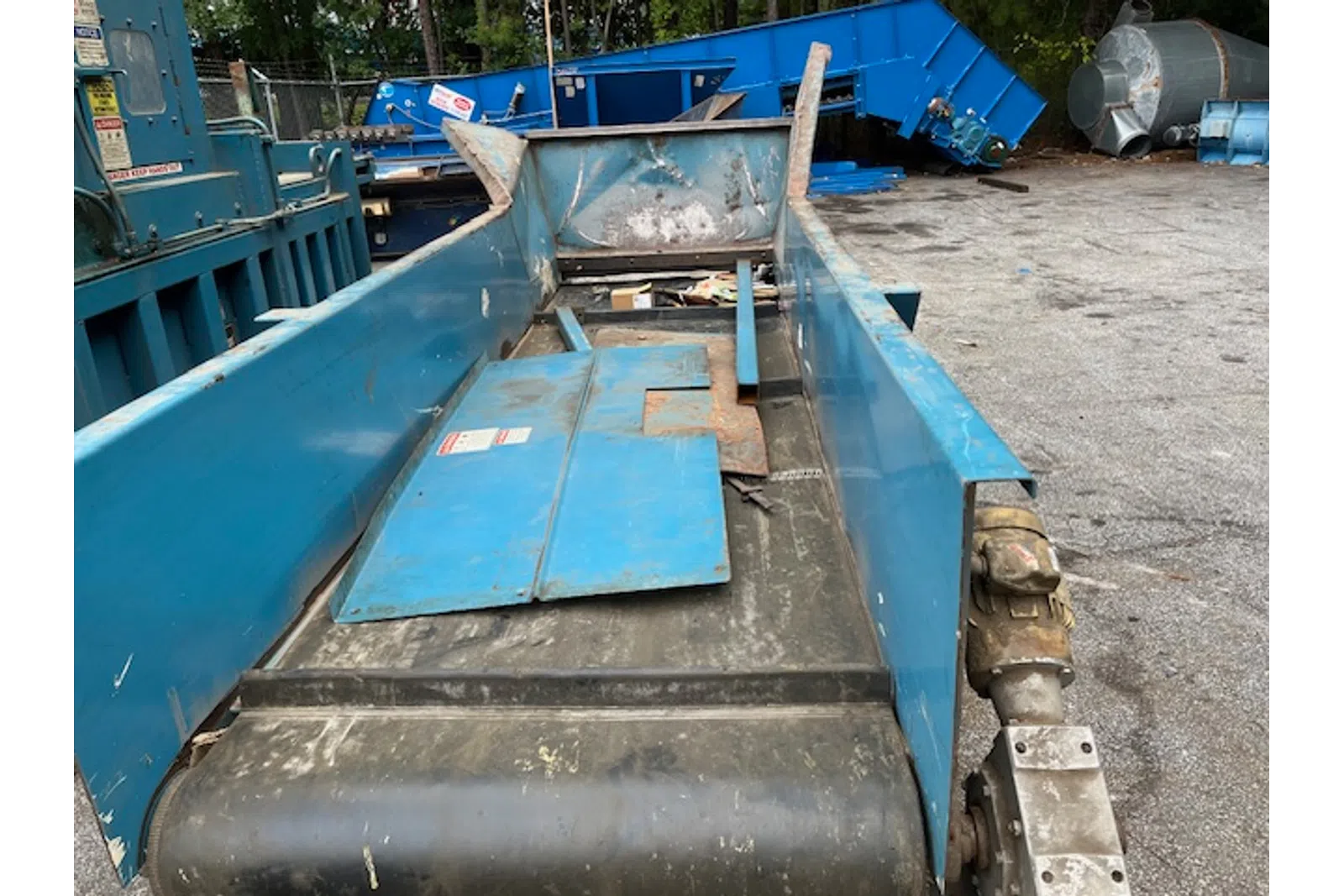 Close-up of an industrial blue conveyor belt system with metal components in an outdoor setting