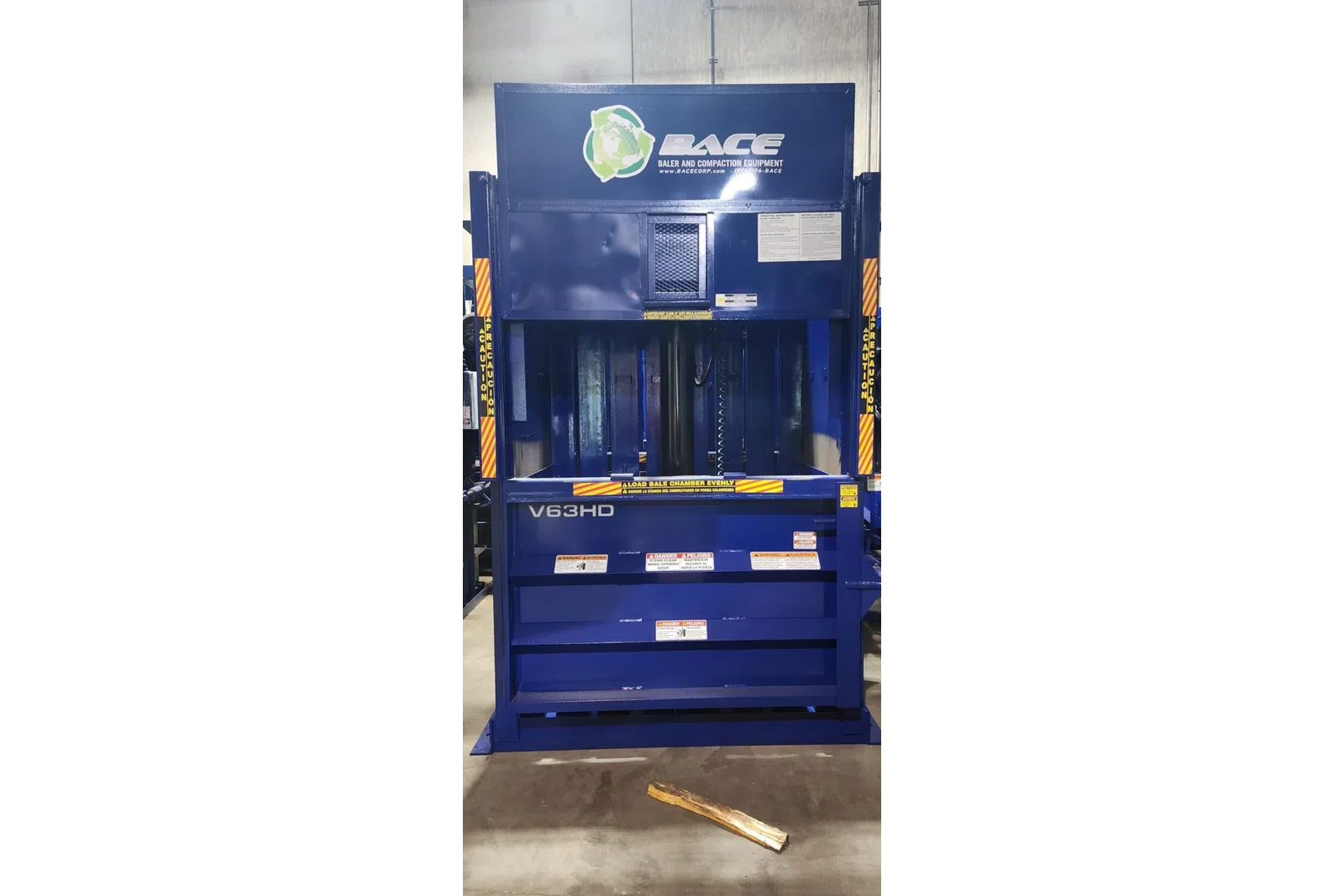 Blue industrial baler machine V63HD by BACE for baling and compaction with safety warning labels