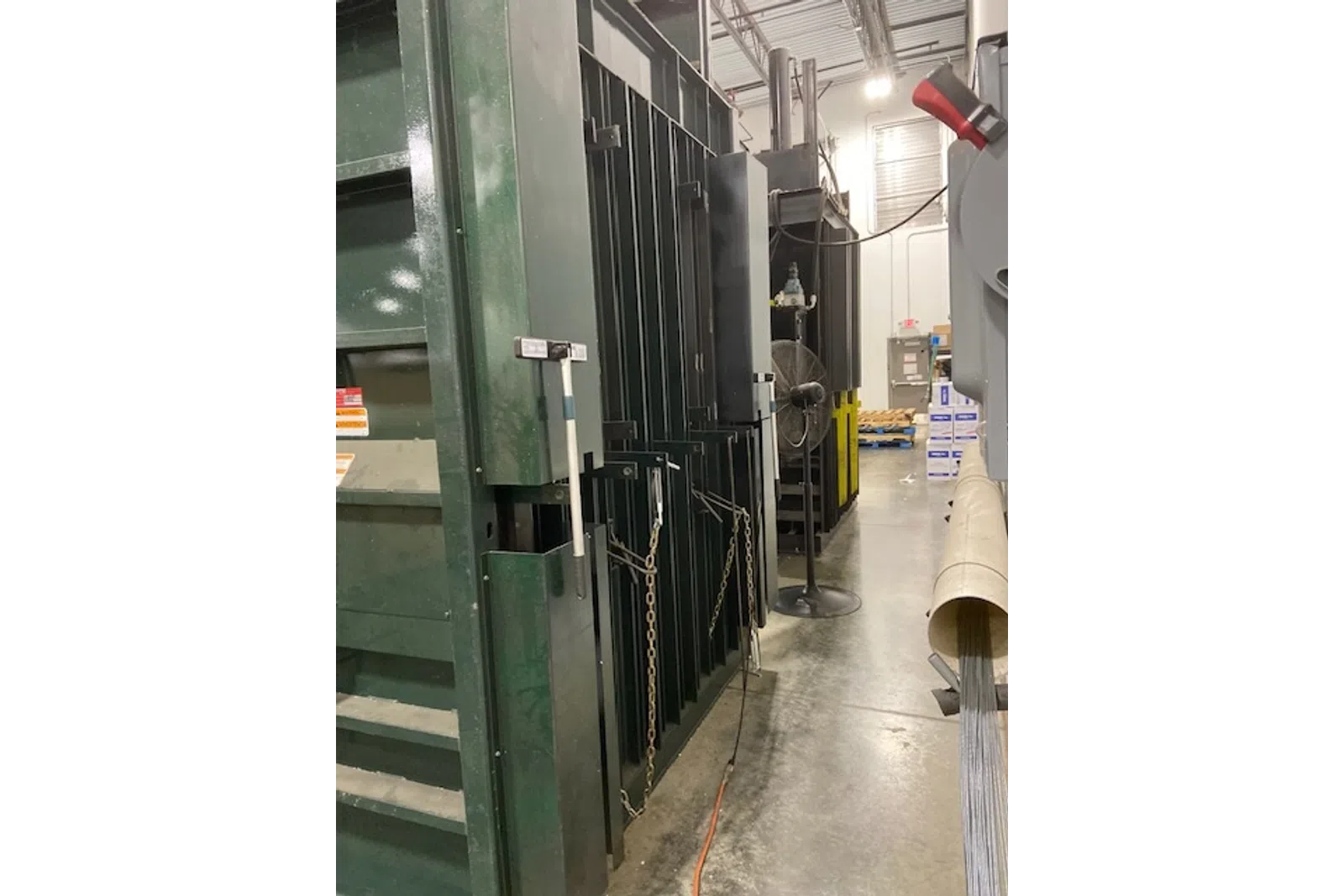 Industrial machinery and equipment lined up in a warehouse with concrete flooring and overhead lighting.