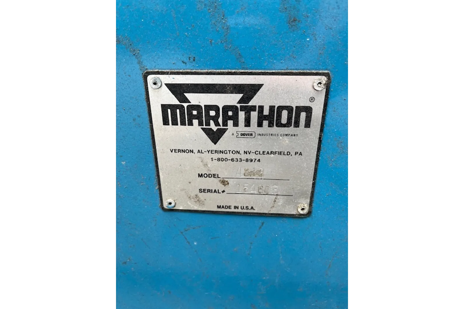 Metal identification plate with Marathon logo and manufacturing details on a blue surface.