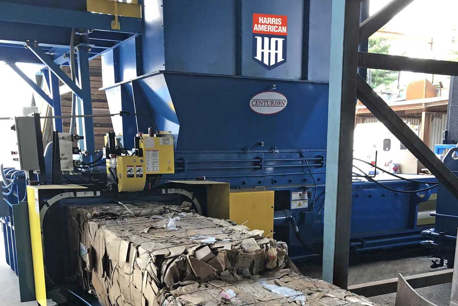 Industrial Harris American cardboard baler compressing and bundling cardboard waste in a factory