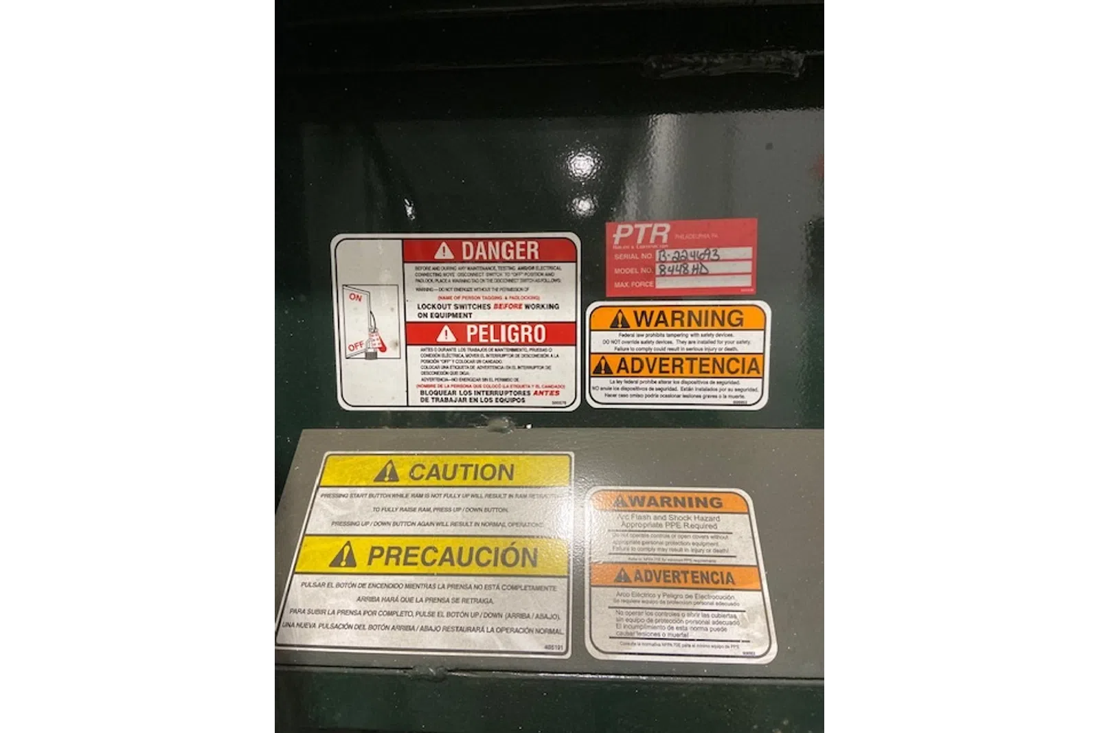 Multiple bilingual safety labels including danger, warning, and caution notices on industrial equipment panel.