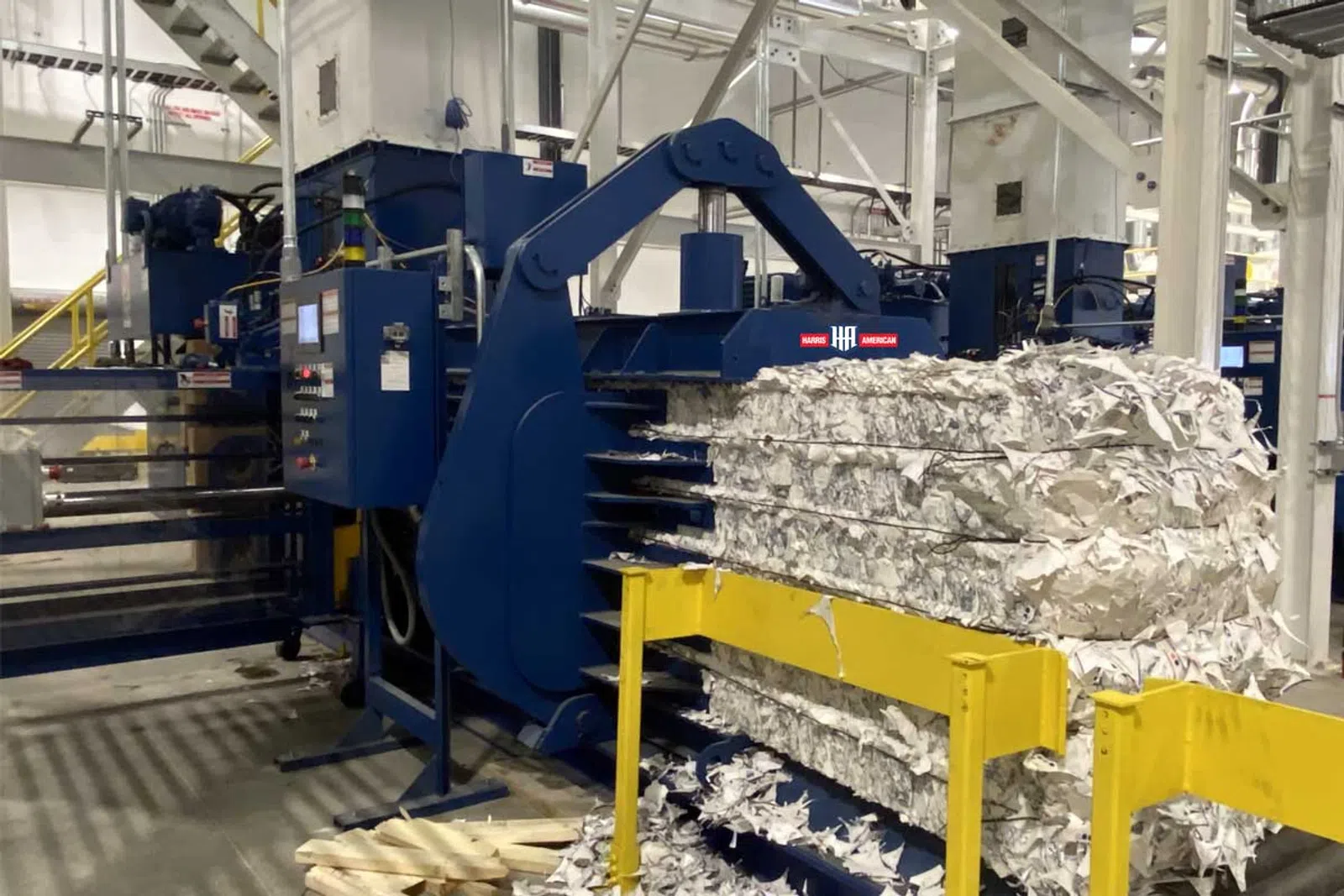 Industrial baler machine compressing large bundles of shredded paper in a recycling facility