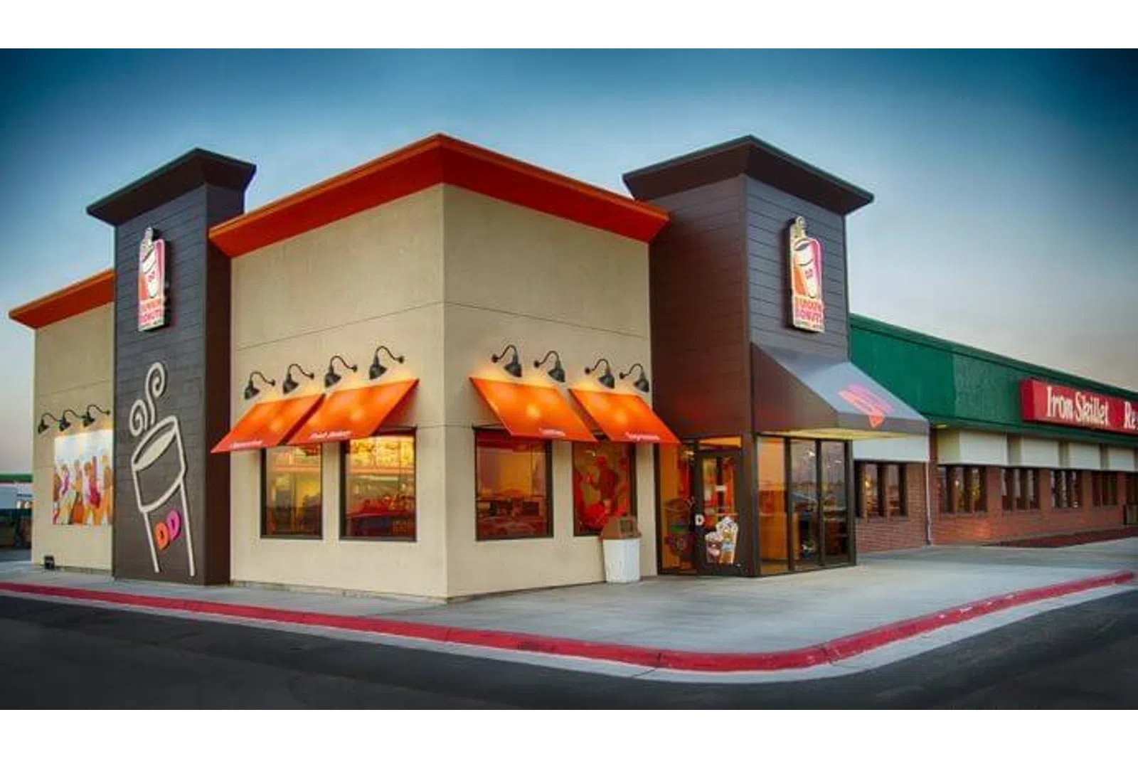 Dunkin' Donuts storefront with orange awnings and coffee cup logo on a clear day