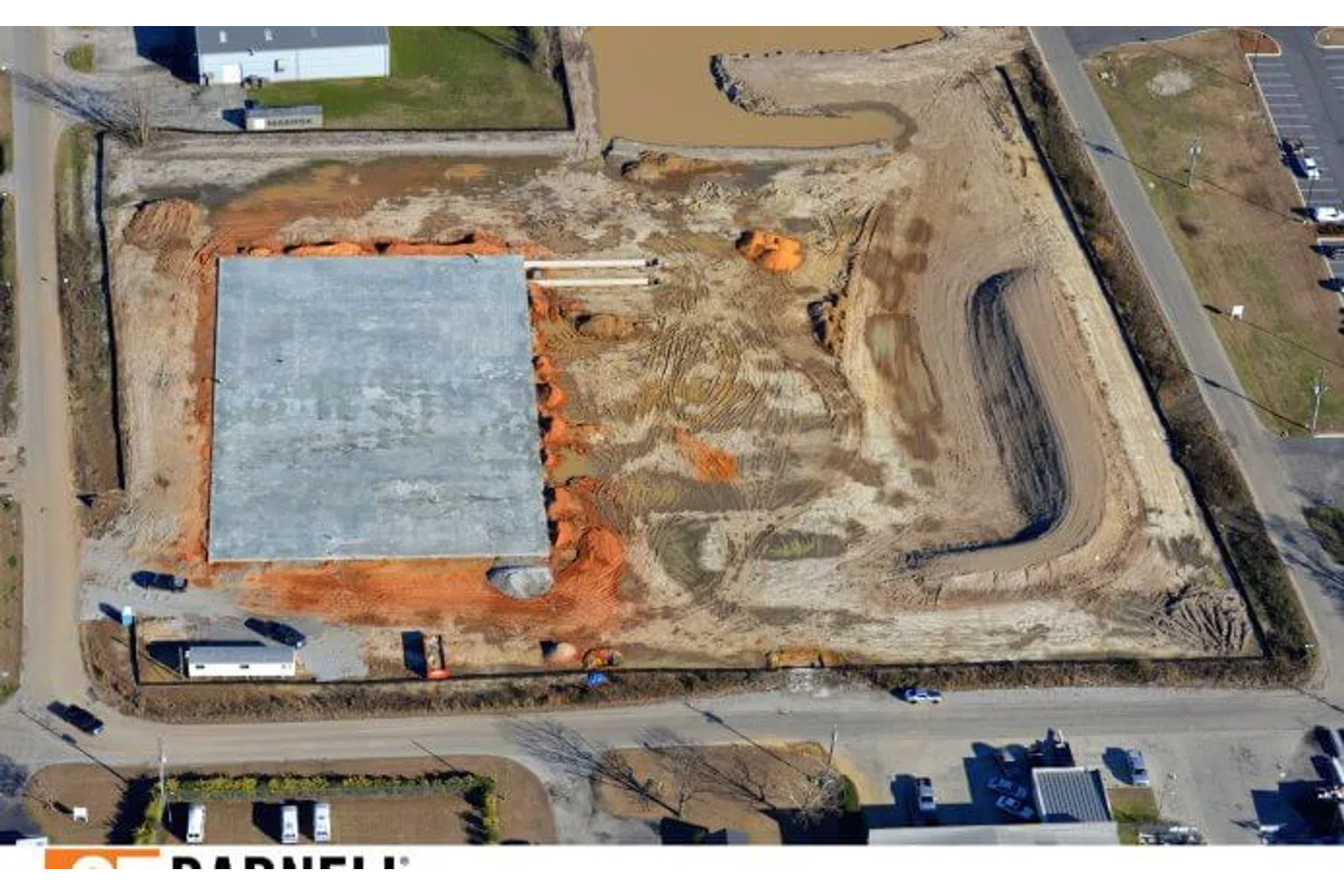 Aerial view of a construction site with concrete foundation and earthmoving activities in progress.