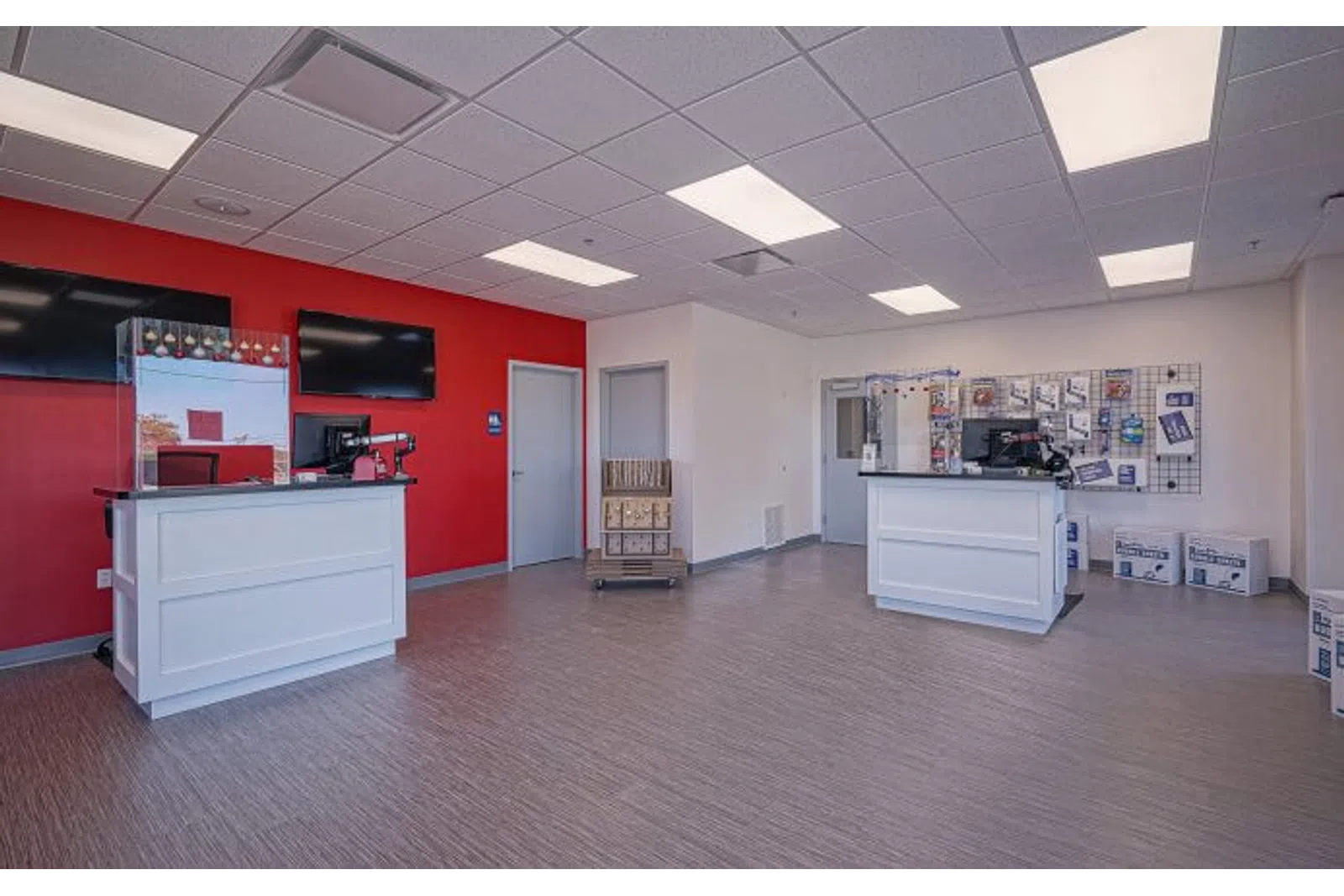 Spacious, modern service area with two white counters, red accent wall, and product displays under fluorescent lighting