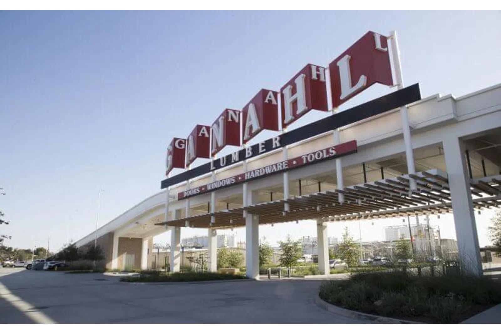 Large Canadian HL Lumber store sign above an entrance with clear sky and parking area.