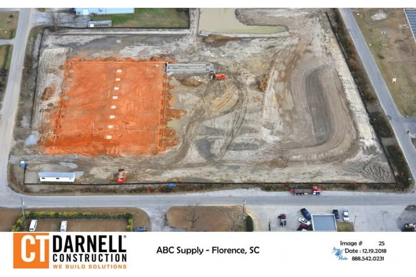 Aerial view of construction site with excavated red soil area and heavy machinery by CT Darnell Construction