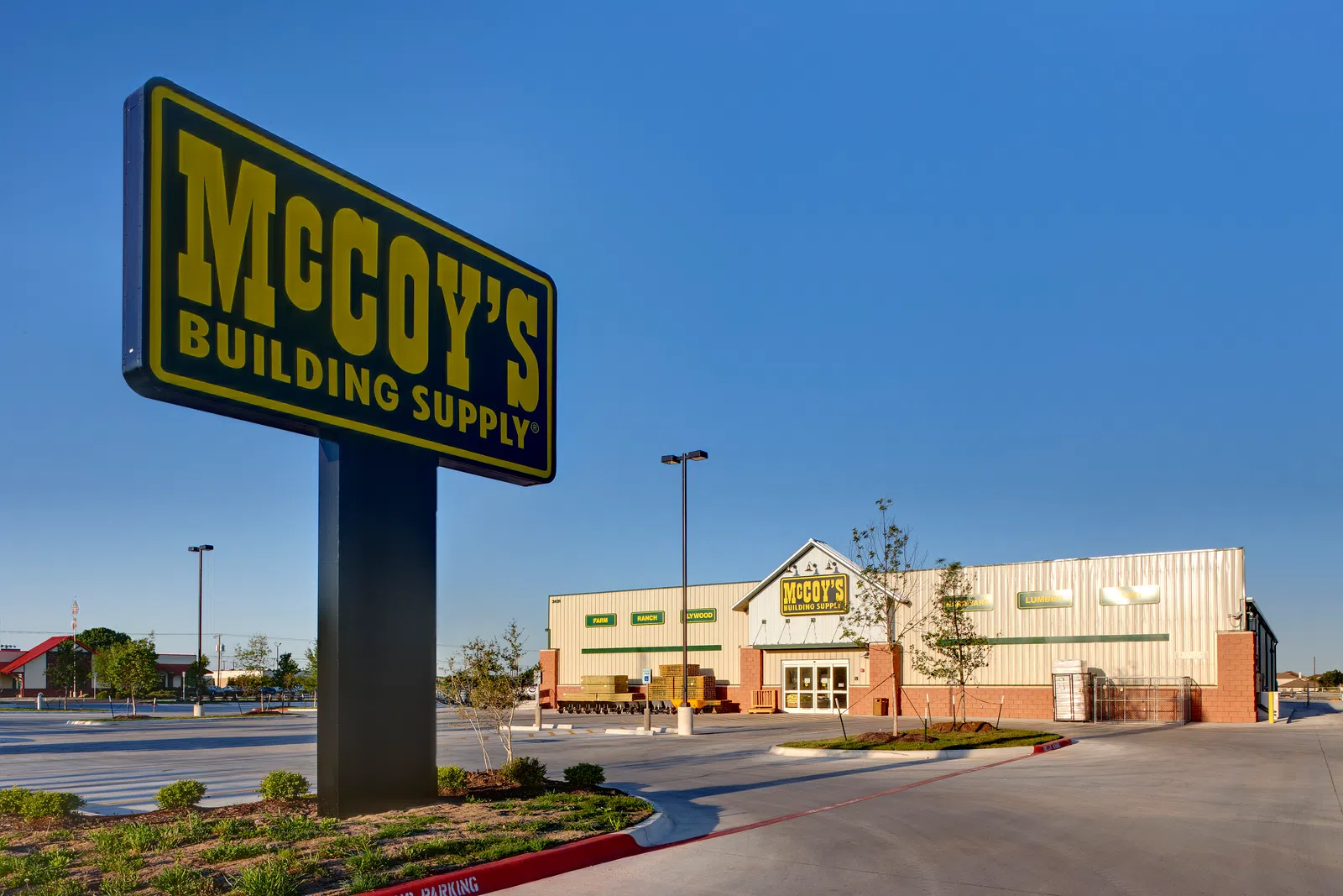 McCoy's Building Supply store and large outdoor sign under clear blue sky in spacious parking lot.