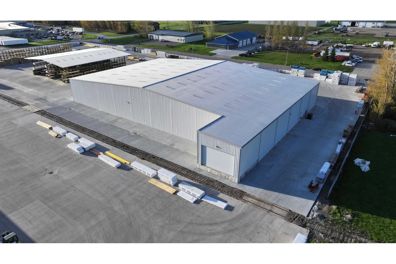 Aerial view of a large industrial warehouse with surrounding storage and concrete pavement in a spacious facility.