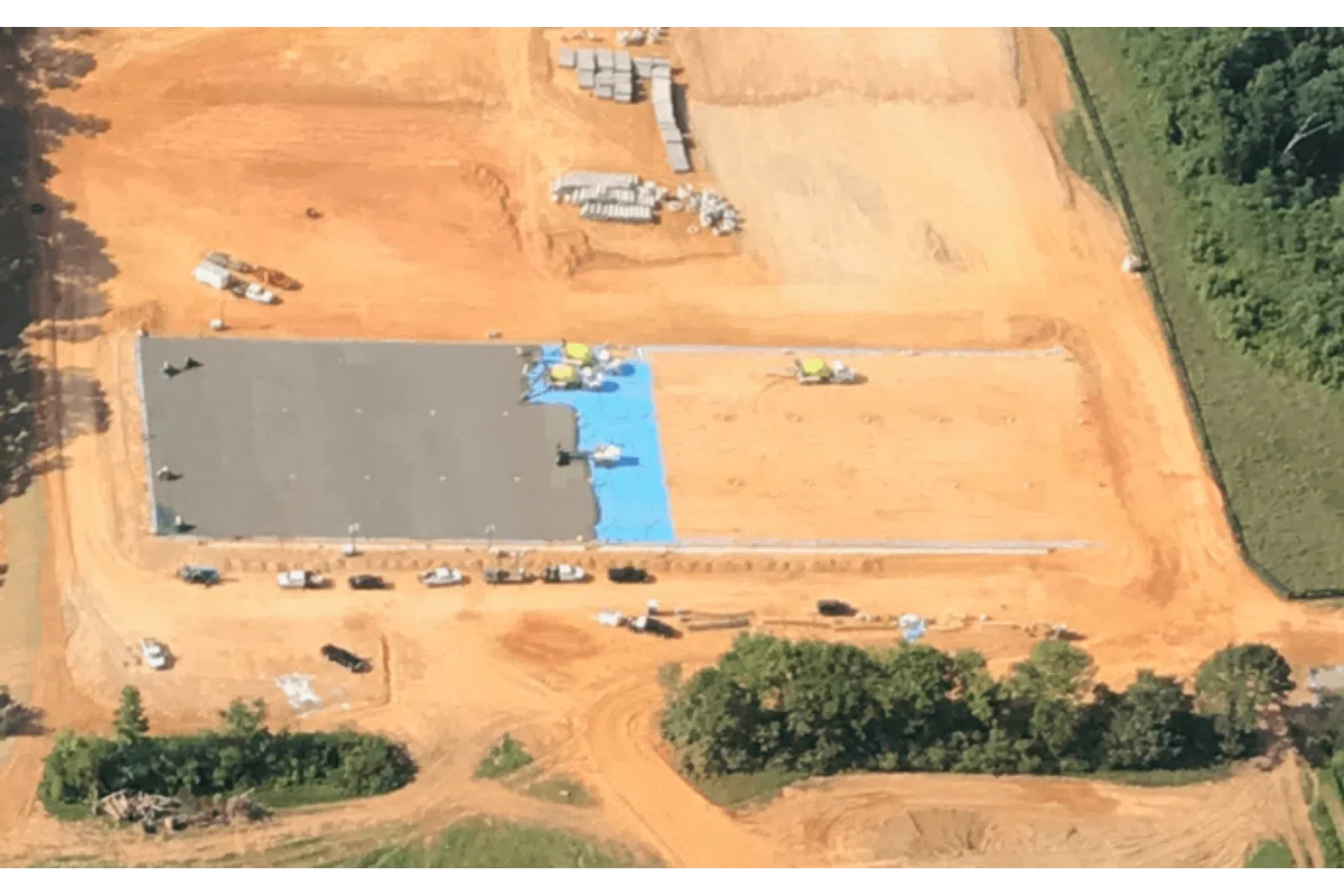 Aerial view of a large construction site with concrete foundation work and surrounding earth moving activities.