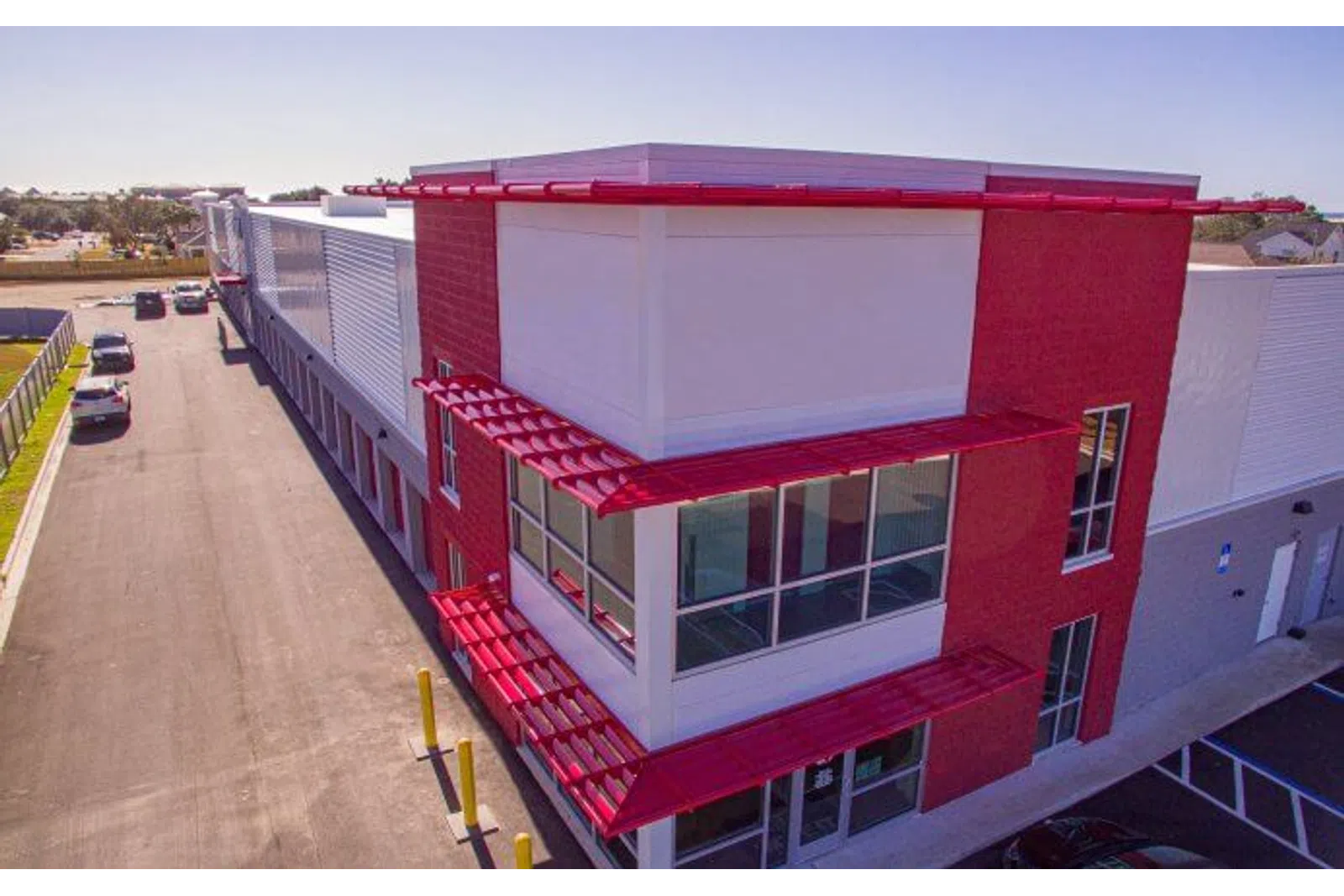 Modern industrial building with white and red exterior and large windows under clear sky.