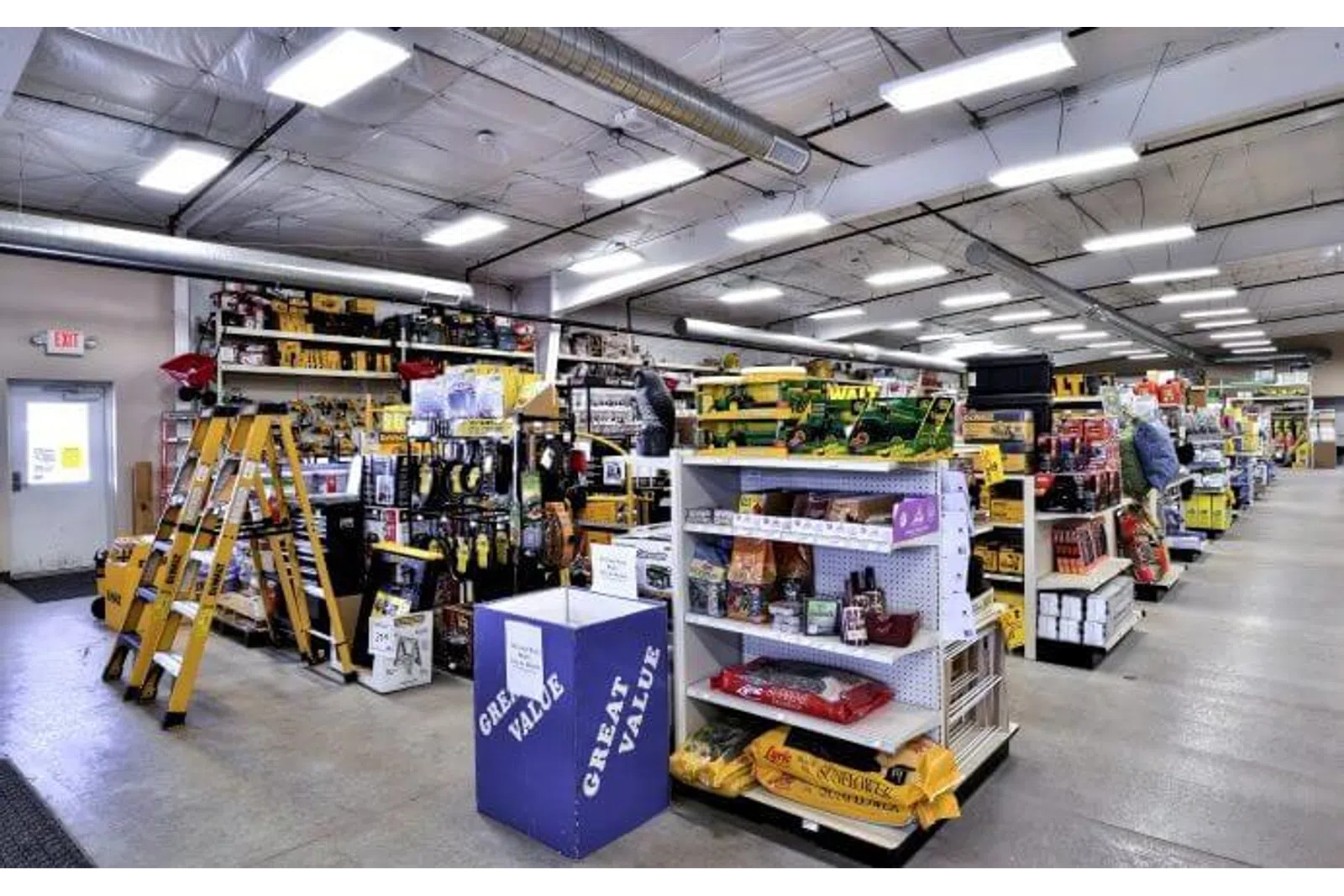 Interior view of a hardware store with ladders, tools, and various construction supplies on display.