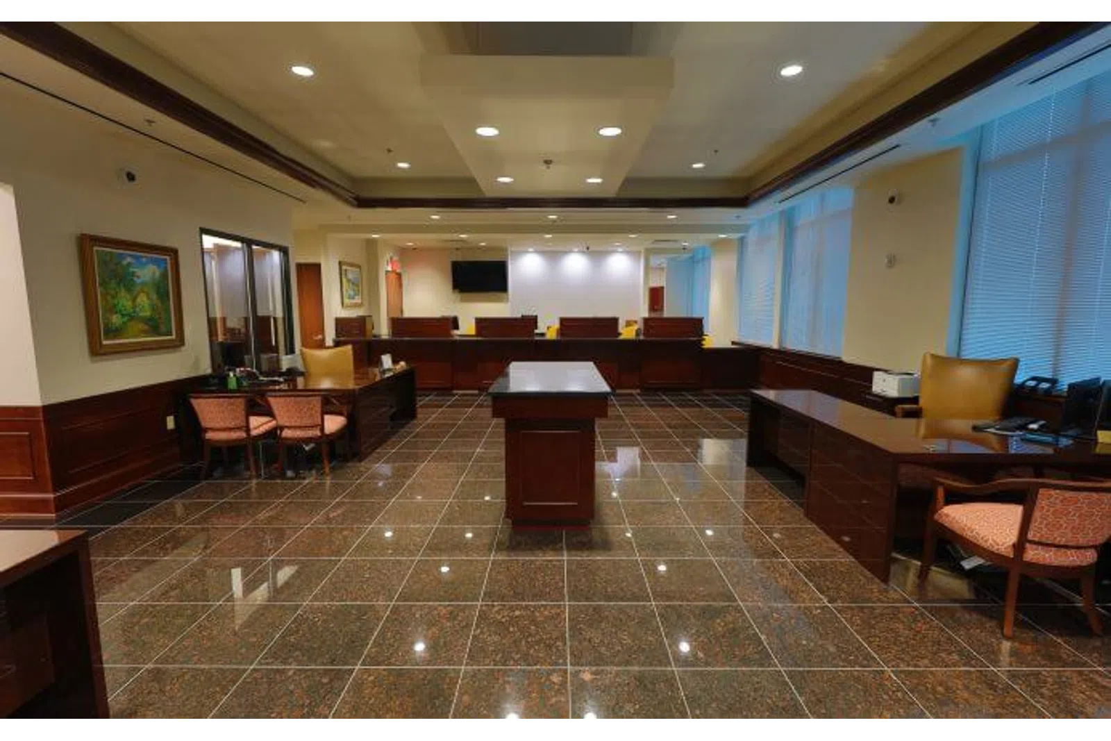 Spacious bank lobby with polished tiled floors, wooden desks, chairs, and large windows with blinds.