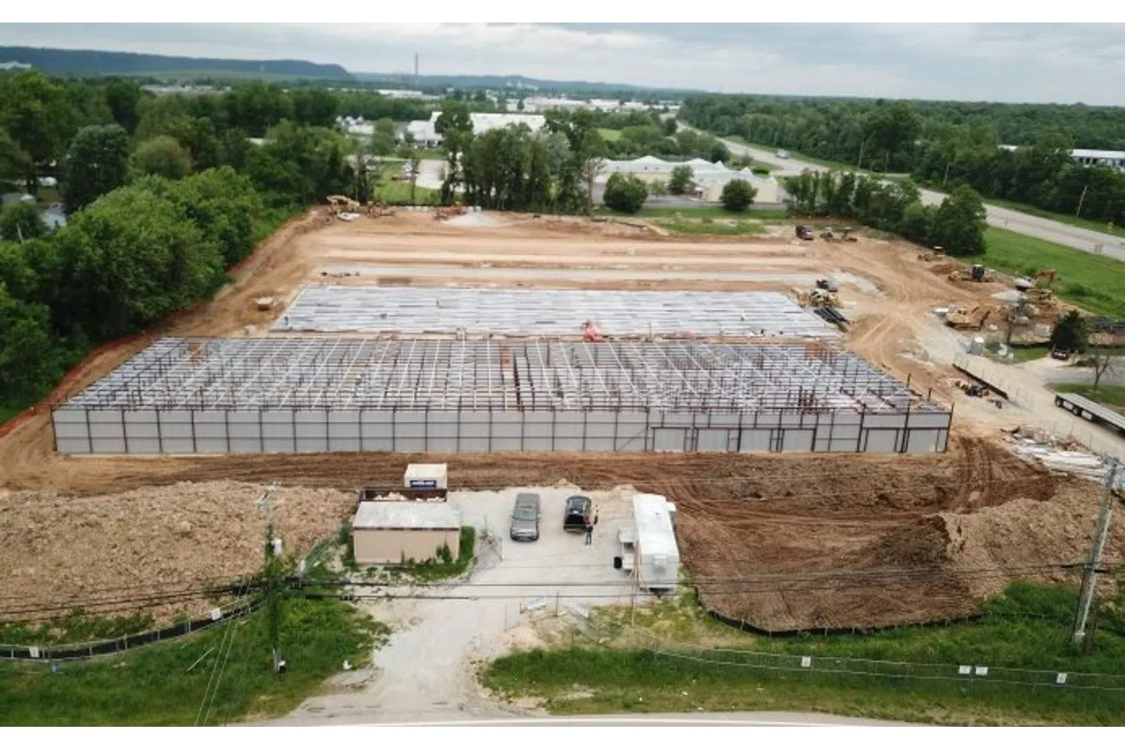 Aerial view of a large industrial building under construction with steel framework and cleared earth around it.