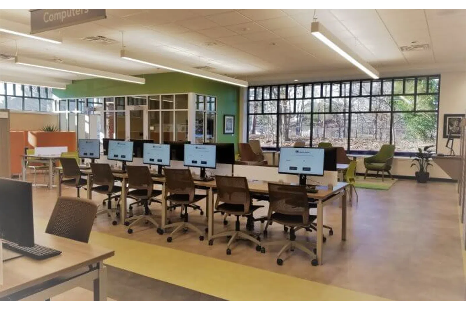 Modern computer lab with multiple workstations, ergonomic chairs, large windows, and bright interior lighting.