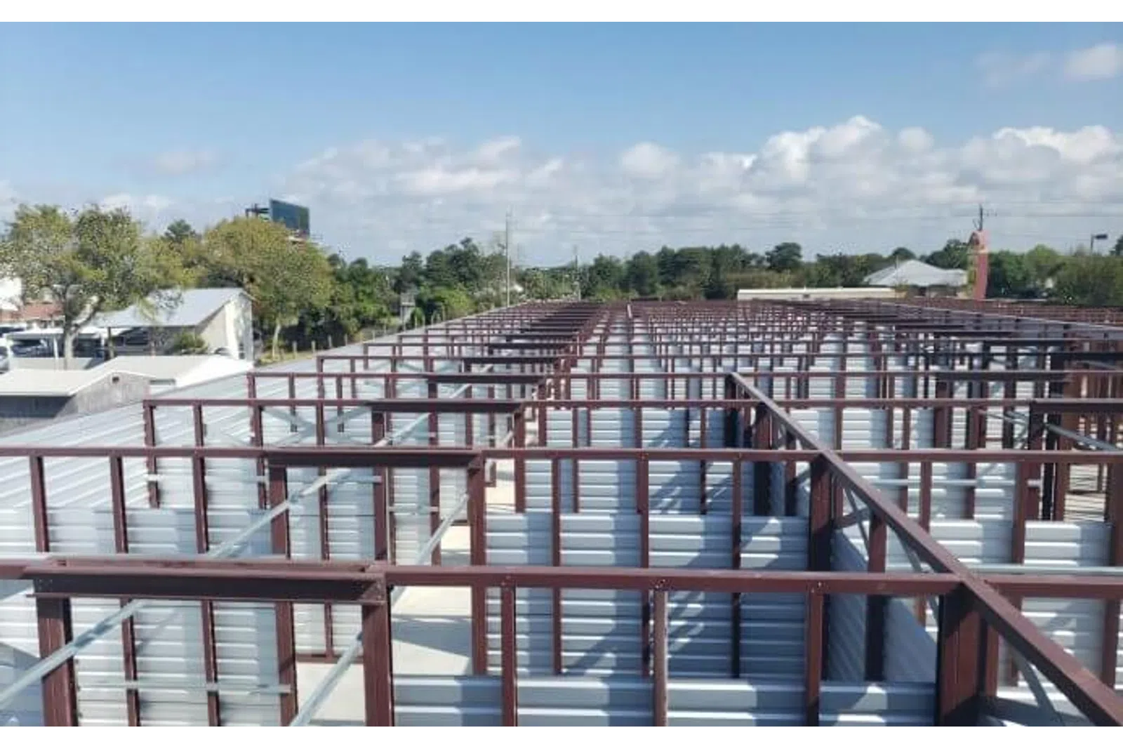 Aerial view of large metal storage units with corrugated walls and steel frames under blue sky.