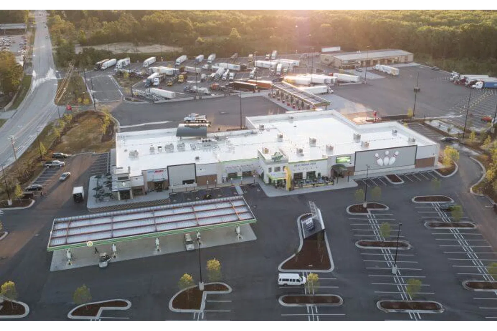 Aerial view of a large convenience store with gas station and trailer parking area during sunset.