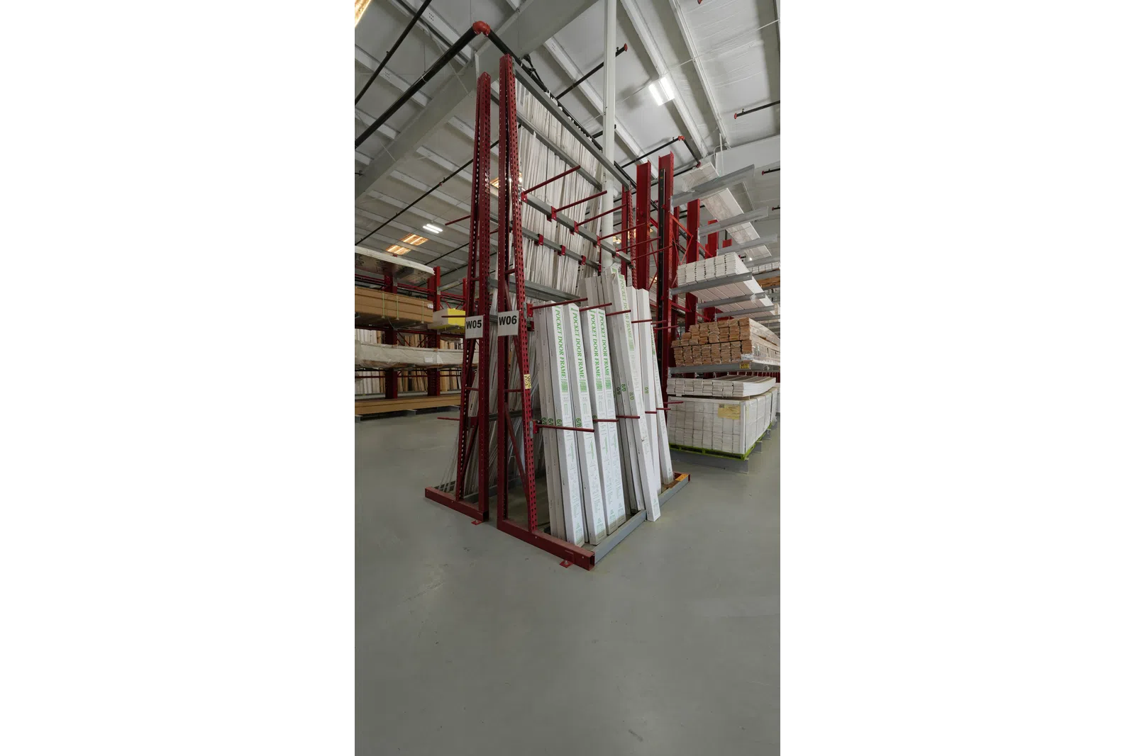 Warehouse racks storing boxed pocket door frames and lumber in an organized industrial setting.