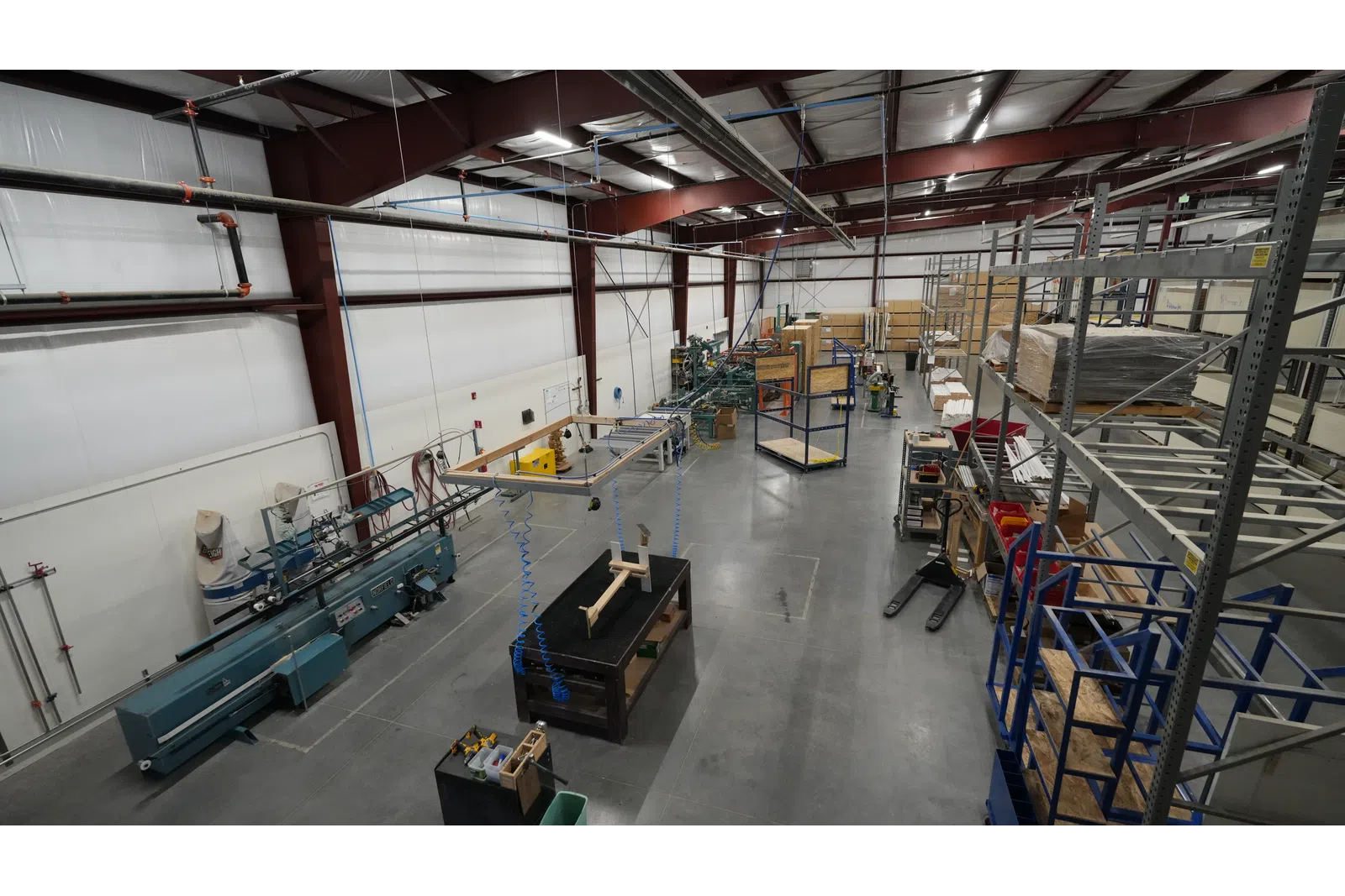Wide view of a clean, organized industrial workshop with machinery, shelving, and workstations under high ceilings.