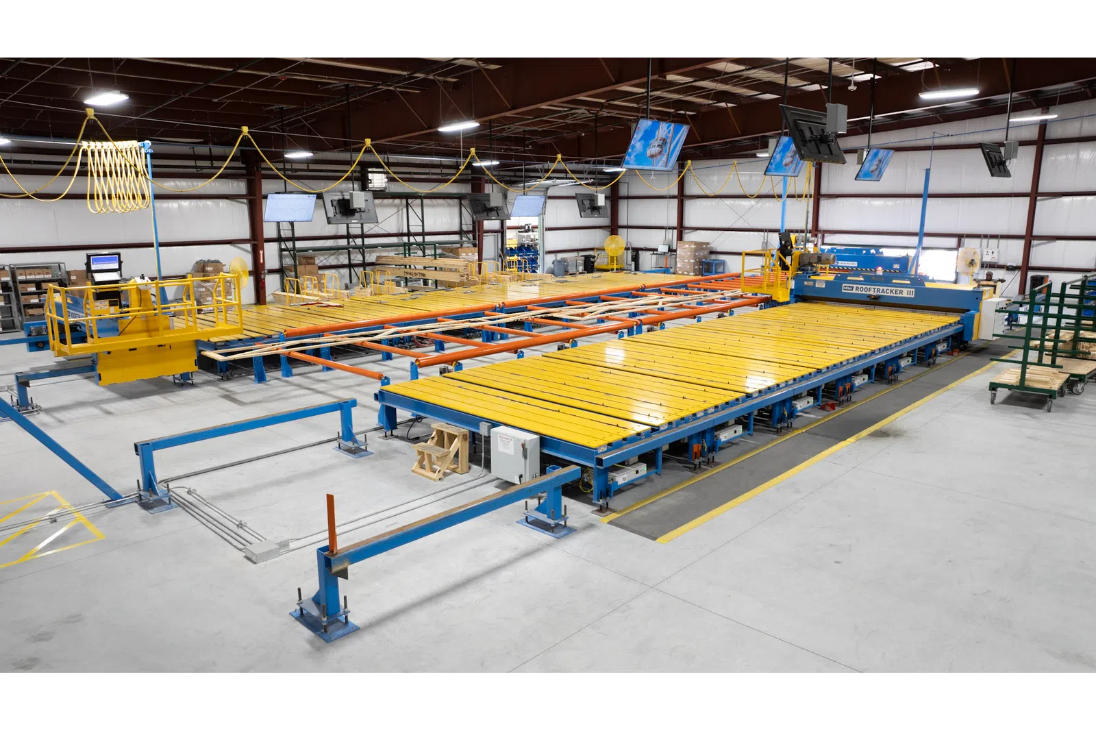 Large industrial machine with yellow and blue components in a spacious factory setting under bright lights