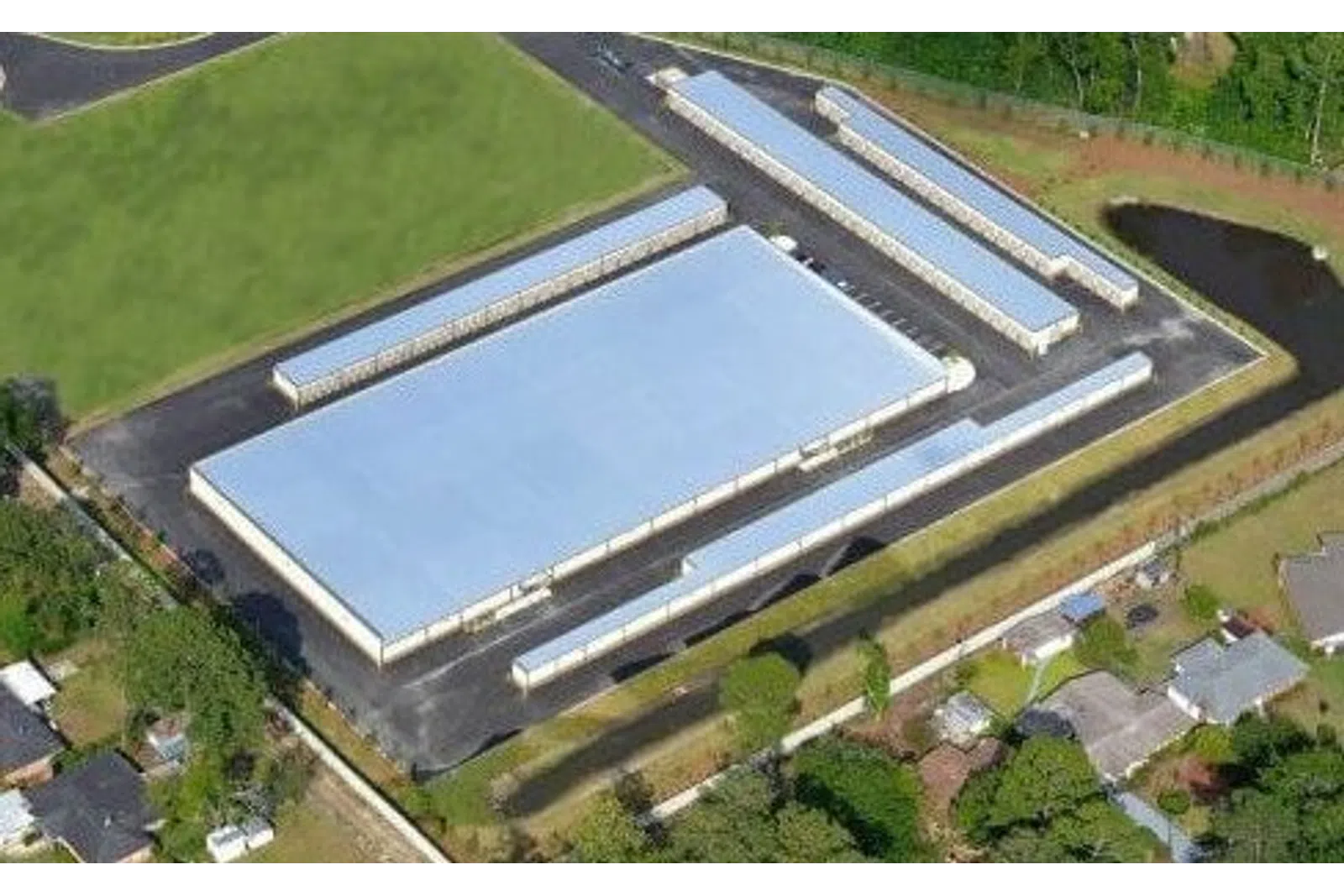 Aerial view of a large warehouse complex with multiple long slim storage units and surrounding greenery.