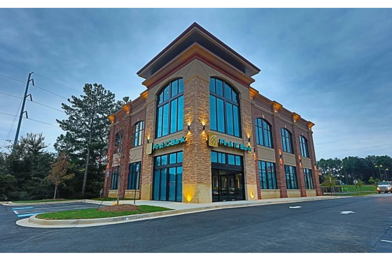 Modern two-story First TC Bank building with large glass windows during twilight under a blue sky.