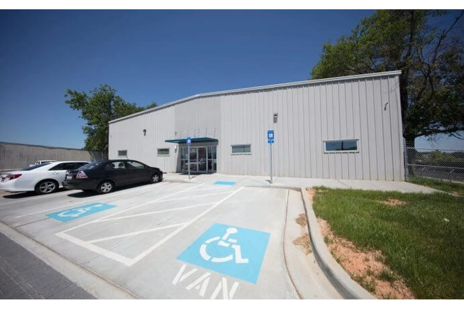 Exterior of a gray commercial building with a parking lot featuring marked handicap and van-accessible spaces.