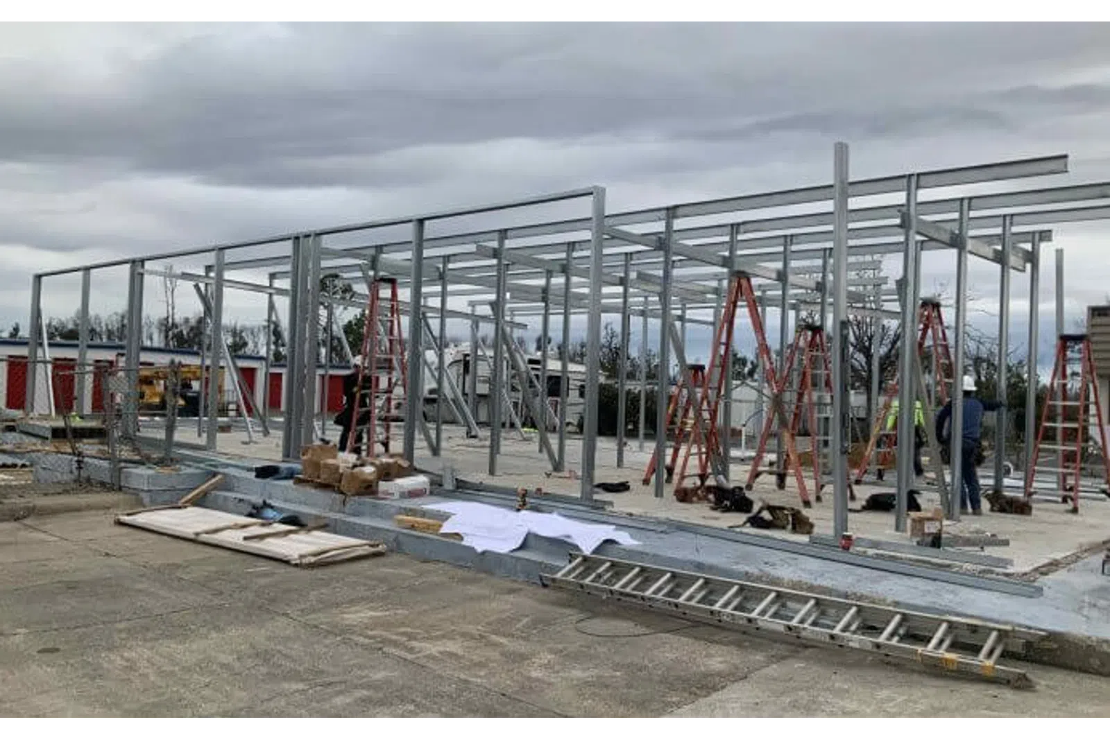Steel frame of a building under construction with ladders and construction materials on a cloudy day