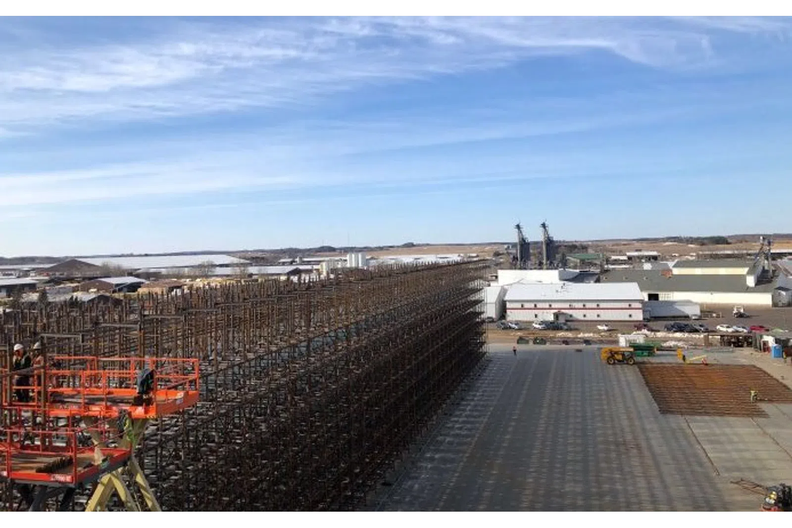 Large industrial storage rack construction at a manufacturing facility under clear blue skies.