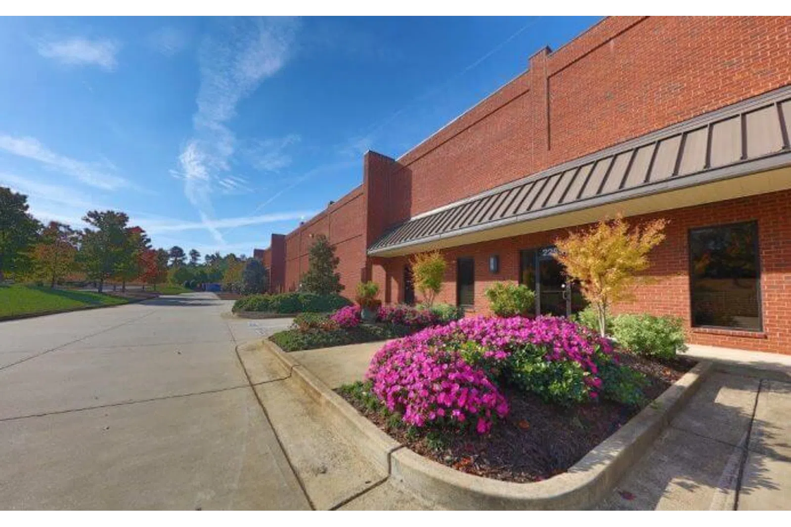 Brick commercial building with landscaped flower beds and clear blue sky on a sunny day.